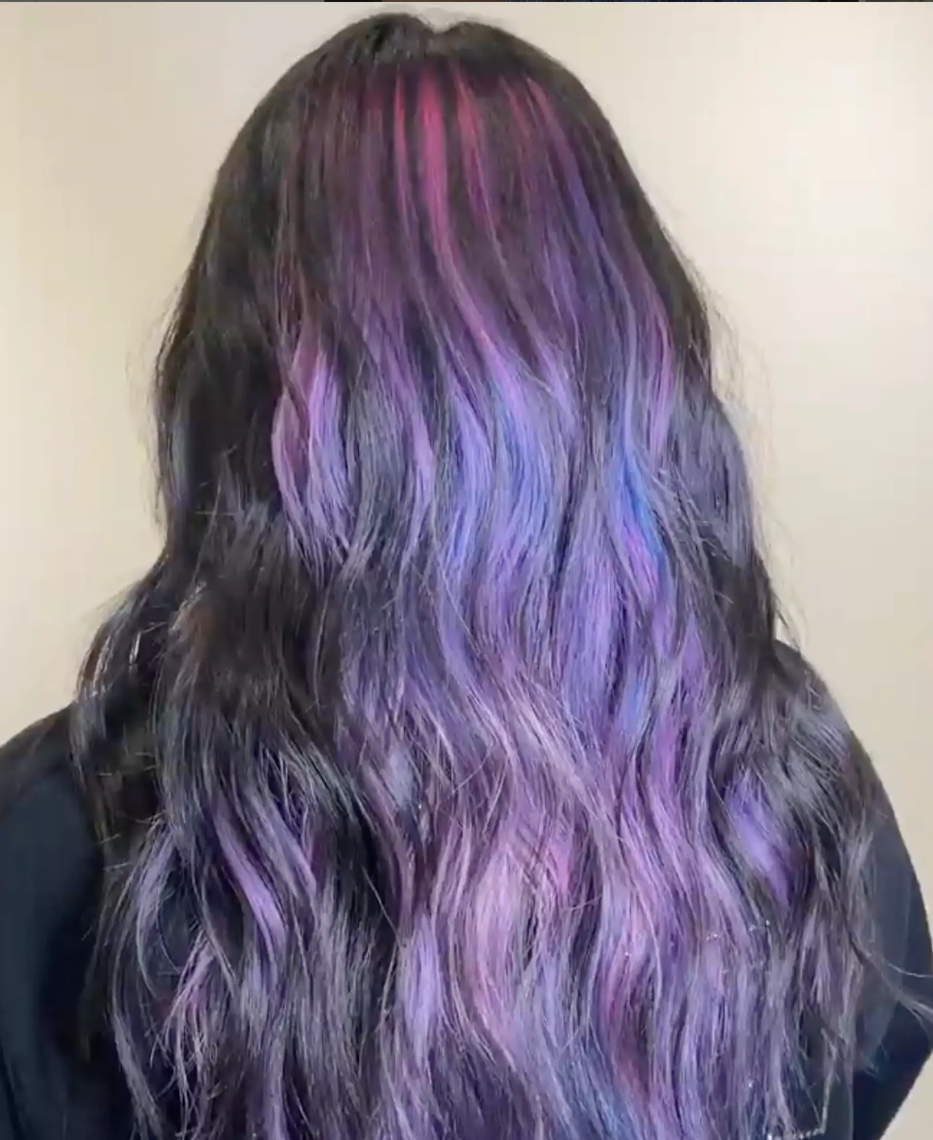 Captivating long wavy hairstyle featuring an ombre effect transitioning from deep black roots to hues of purple, lavender, and indigo with soft, natural waves and subtle layering to enhance volume and movement. 2