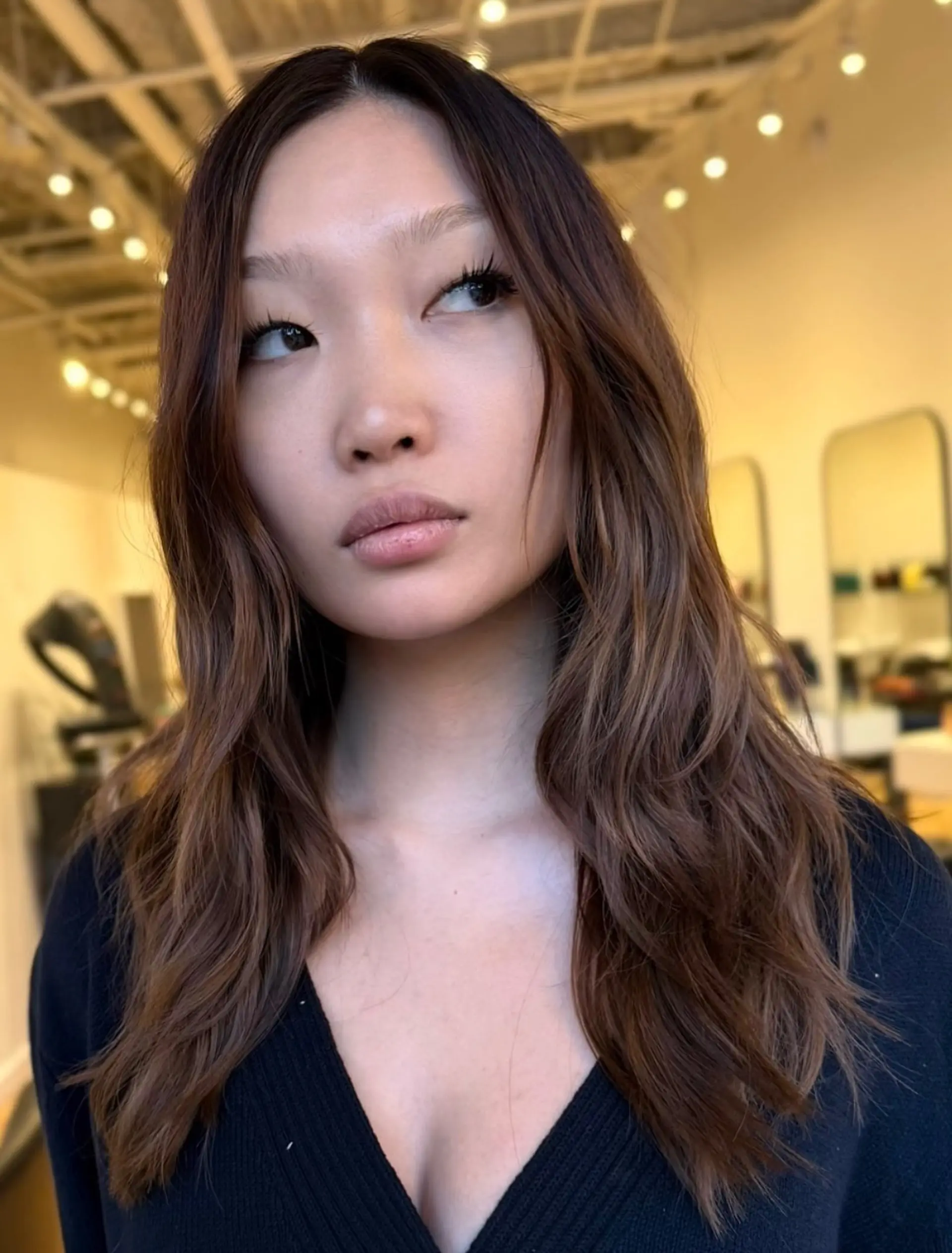 Long dark brown hair styled with loose center-parted waves and soft face-framing layers. 1
