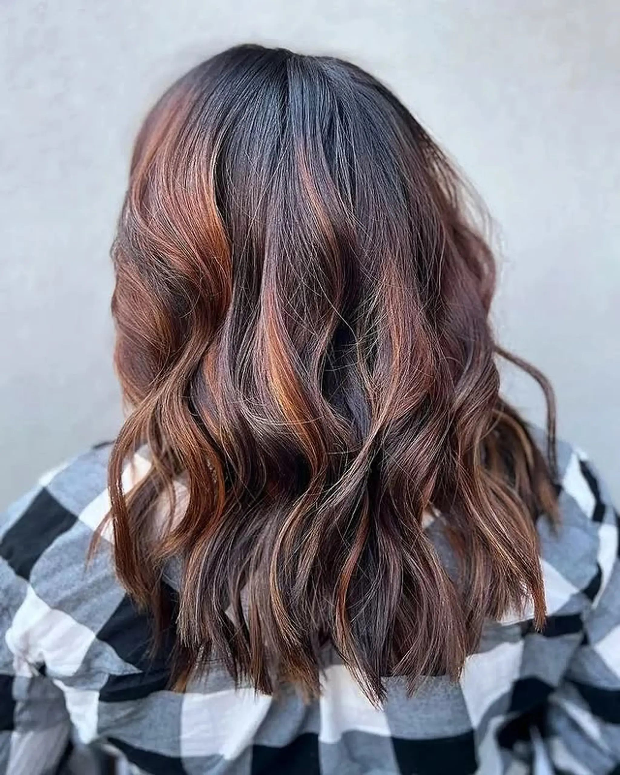 Medium-length wavy hair with copper and auburn balayage.