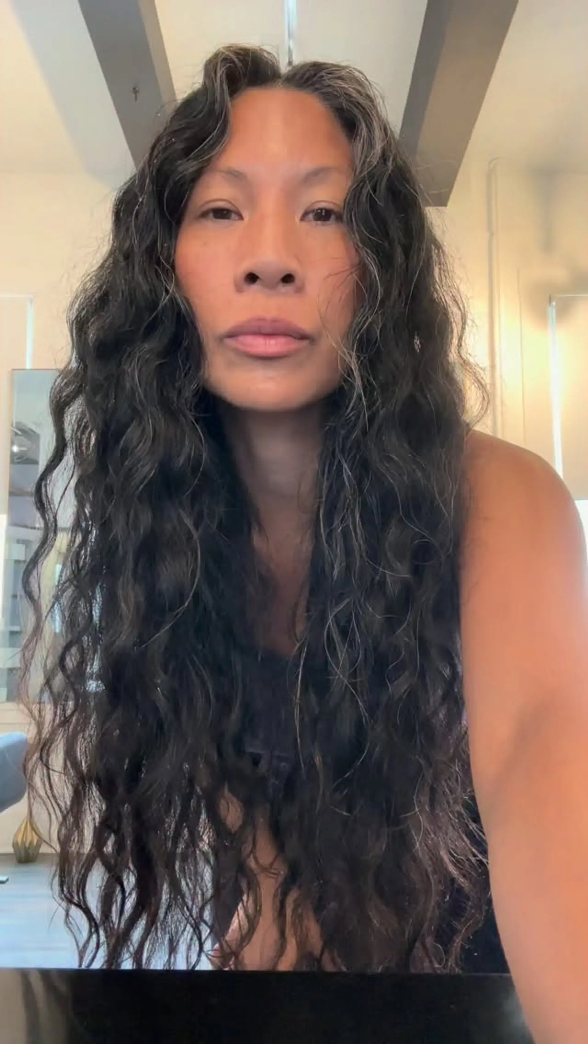 Extra-long dark hair styled in cascading, tousled waves with natural silver strands throughout. 1