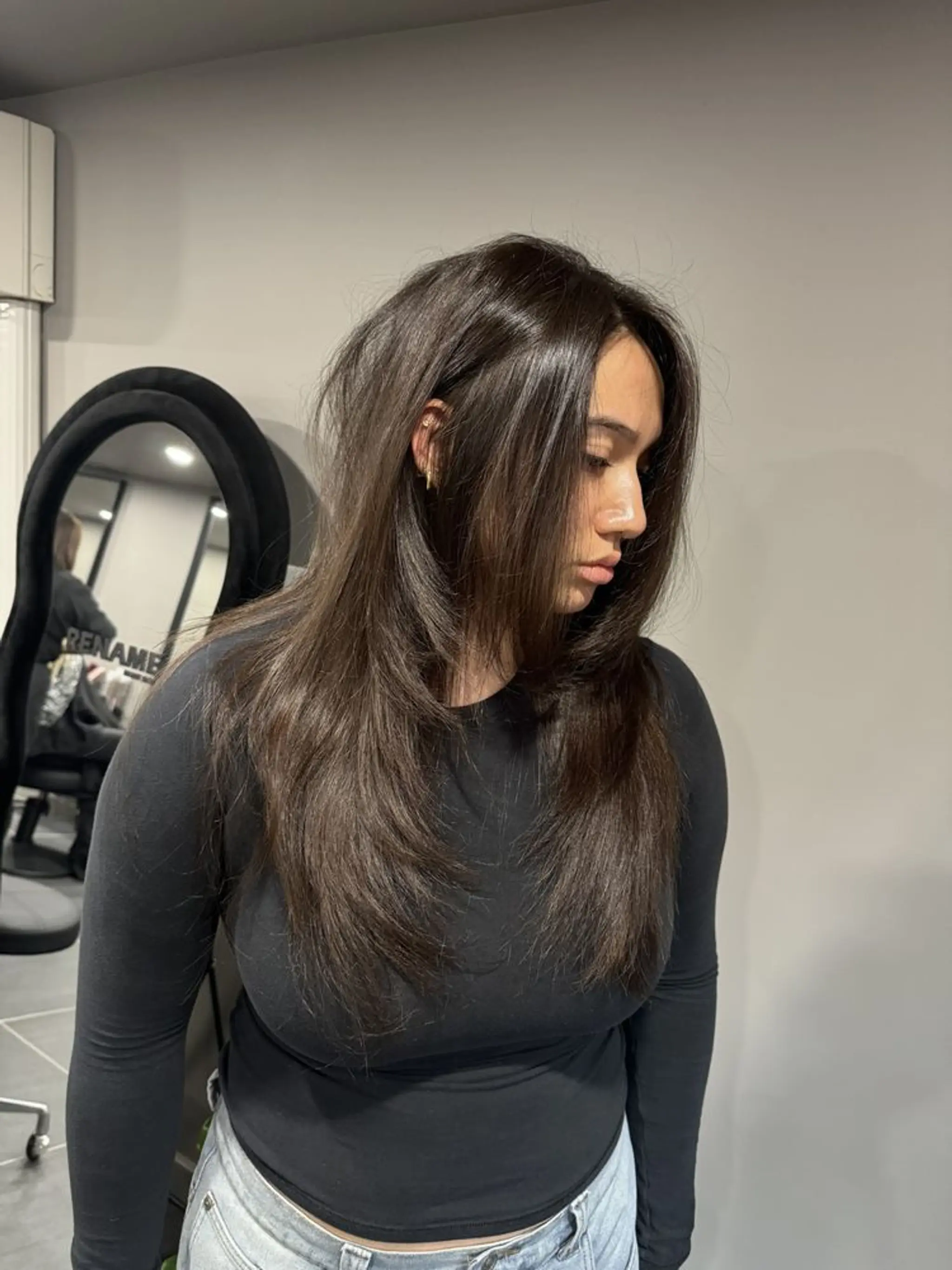 Beautifully sleek cascade of dark brown layers with a side part, featuring medium-length straight hair styled smoothly and naturally, accentuated with dynamic layered cuts.