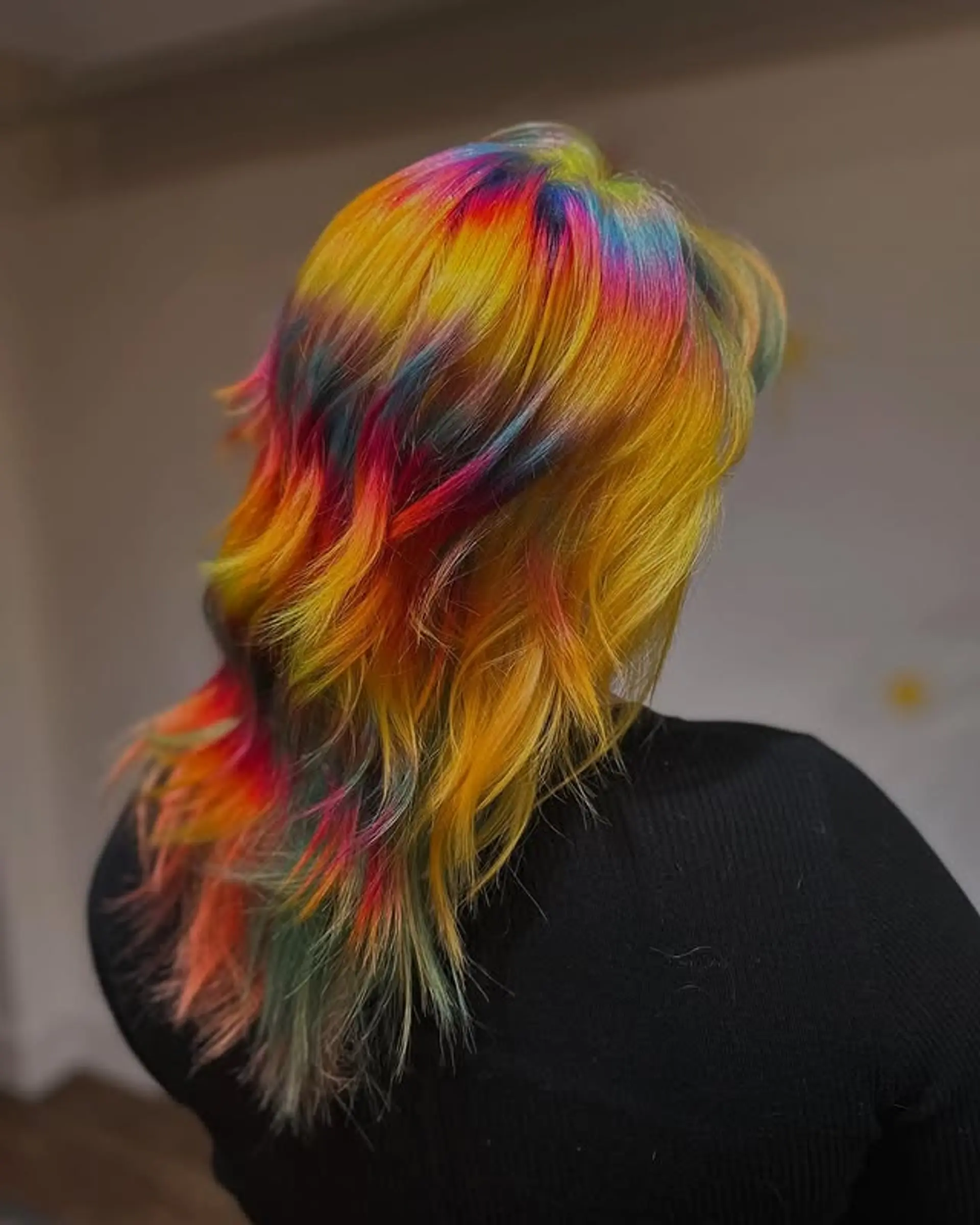 A medium-length wavy shag mullet hairstyle with layers and a rainbow color palette. 1