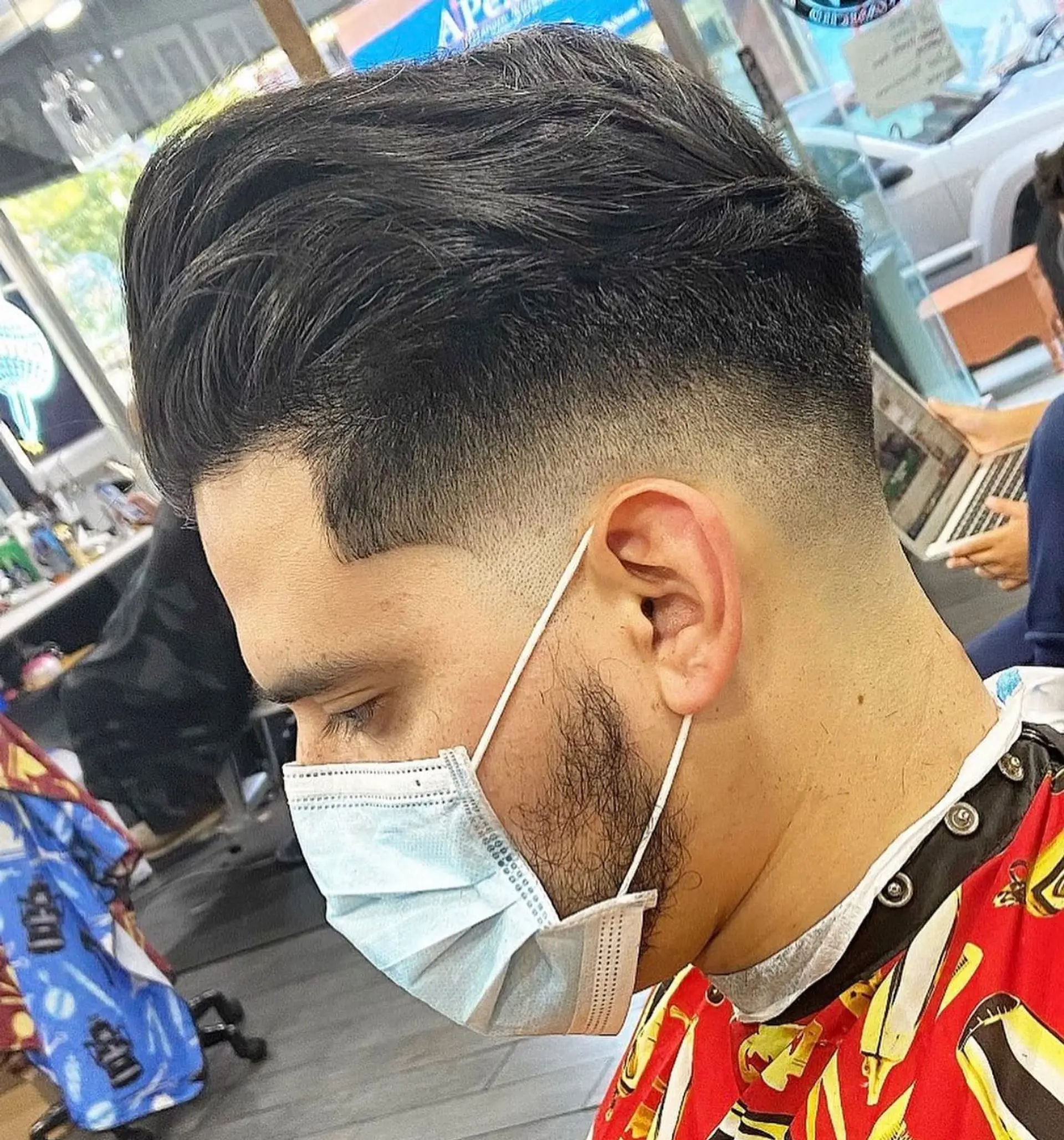 A precise mid skin fade with crisp line-up along the temples, blended into a voluminous textured top swept back. 1