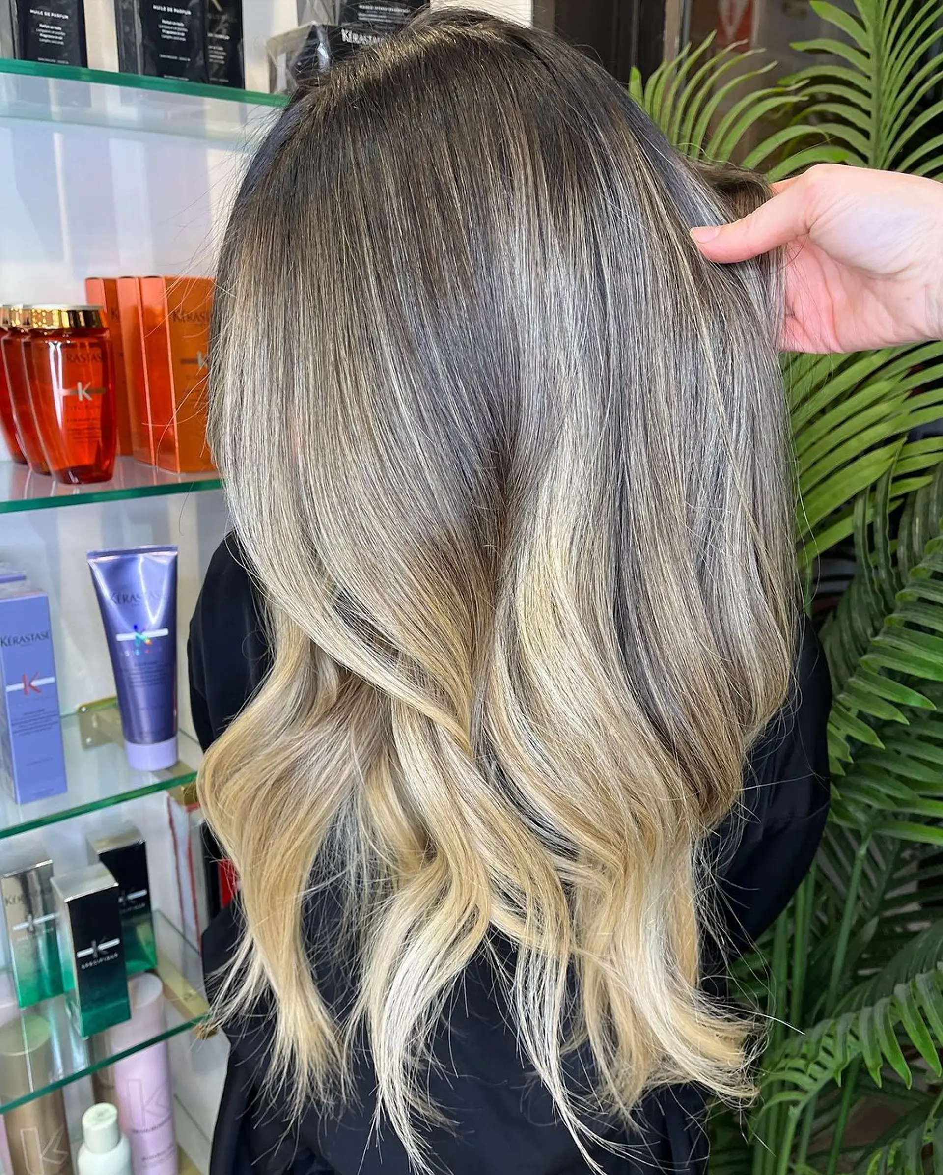 The hairstyle features long, wavy hair crafted with a dark blonde base and gradual platinum and ash blonde balayage highlights, styled in soft beach waves. 1
