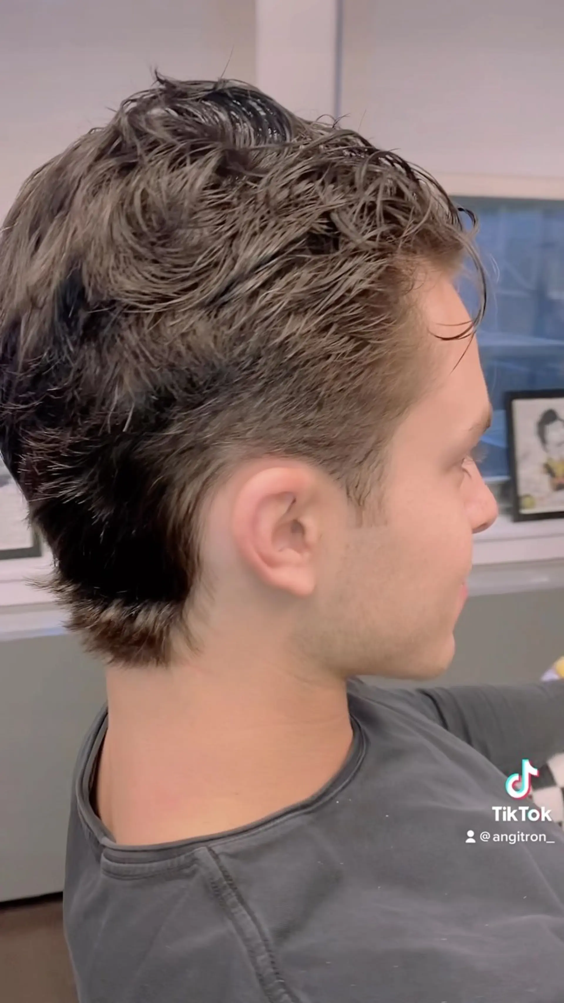 A modern short mullet featuring textured wavy styling on top, tapered sides around the ear, and extended length down the nape. 1
