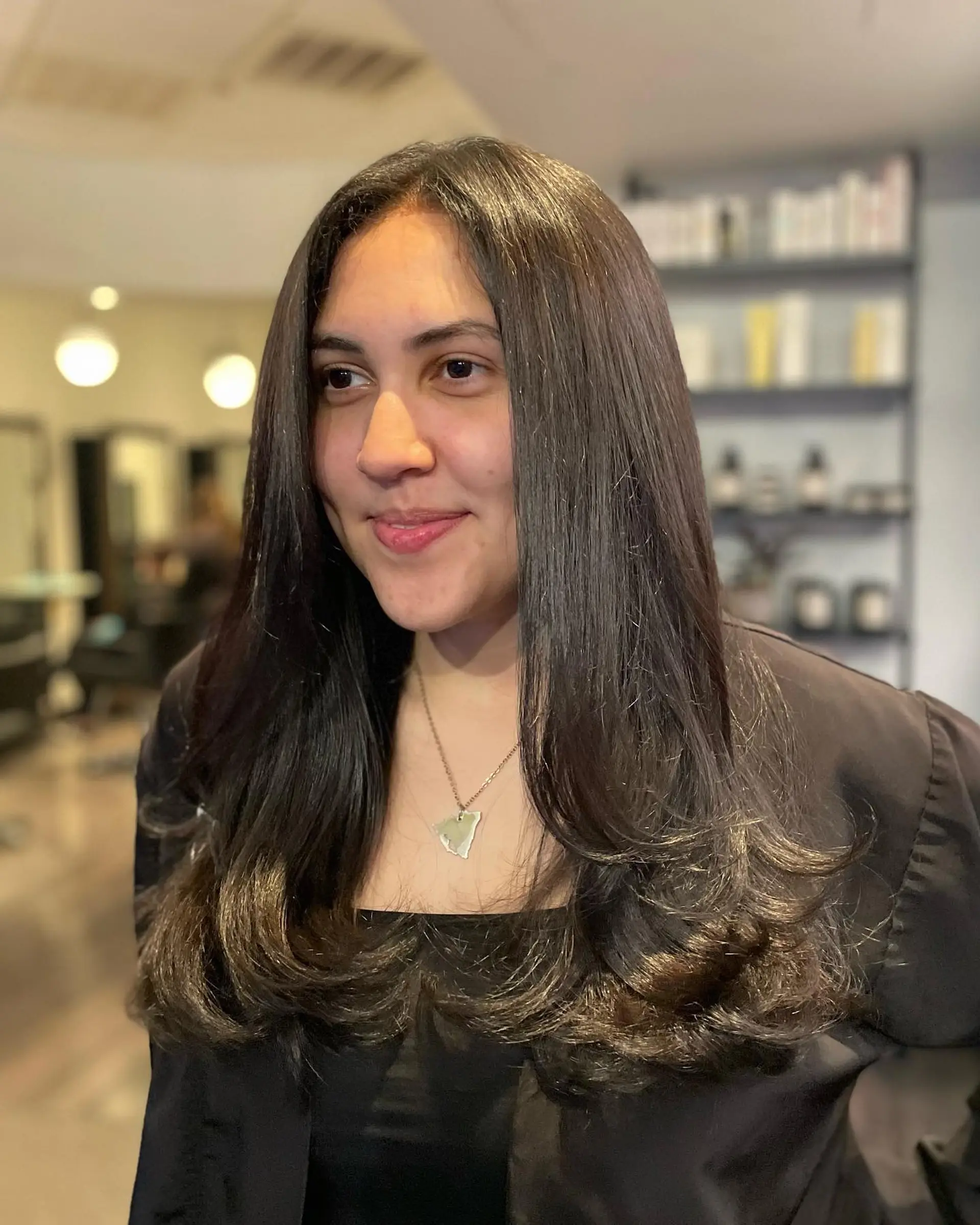 Long, glossy dark roast brunette hair styled straight with voluminous, curled-up ends and subtle face framing. 1