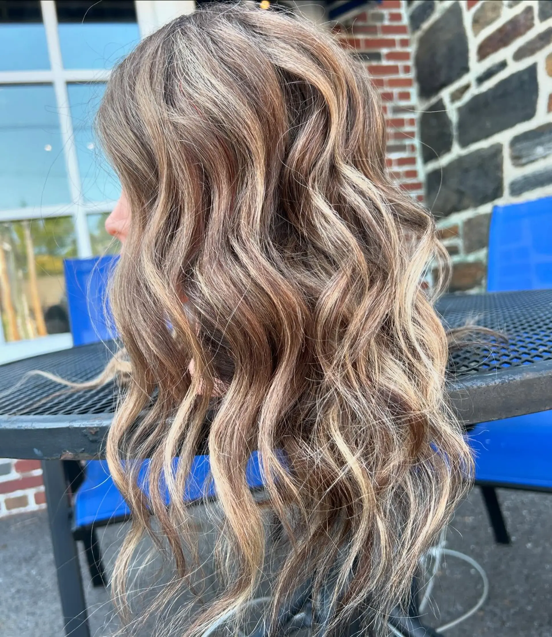 Long dimensional hair featuring a blend of bright blonde highlights and light brown lowlights styled in loose, textured waves. 1