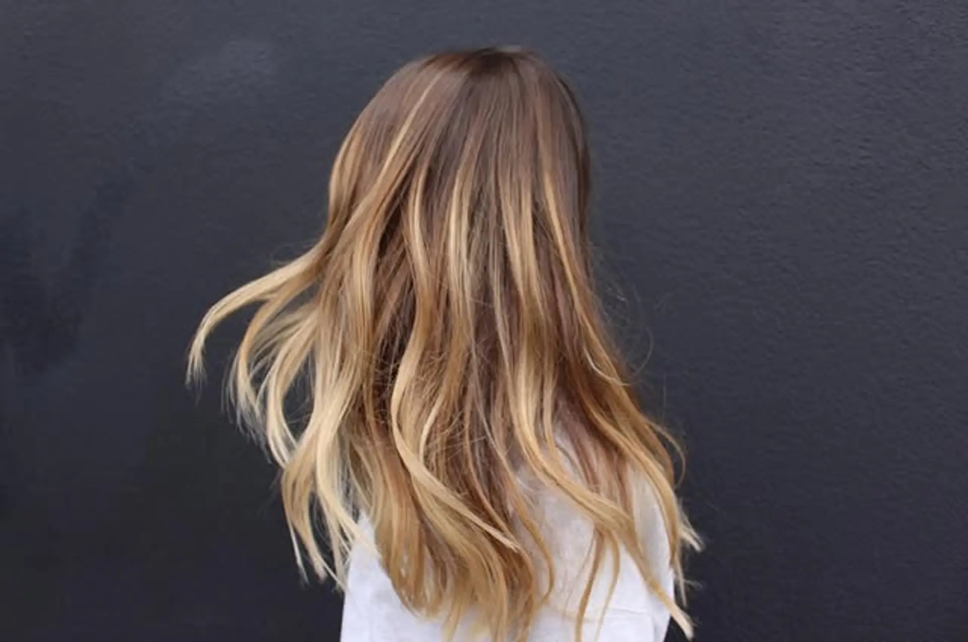 Long, wavy hair with a balayage that transitions from dark roots to a golden blonde ombre. 1