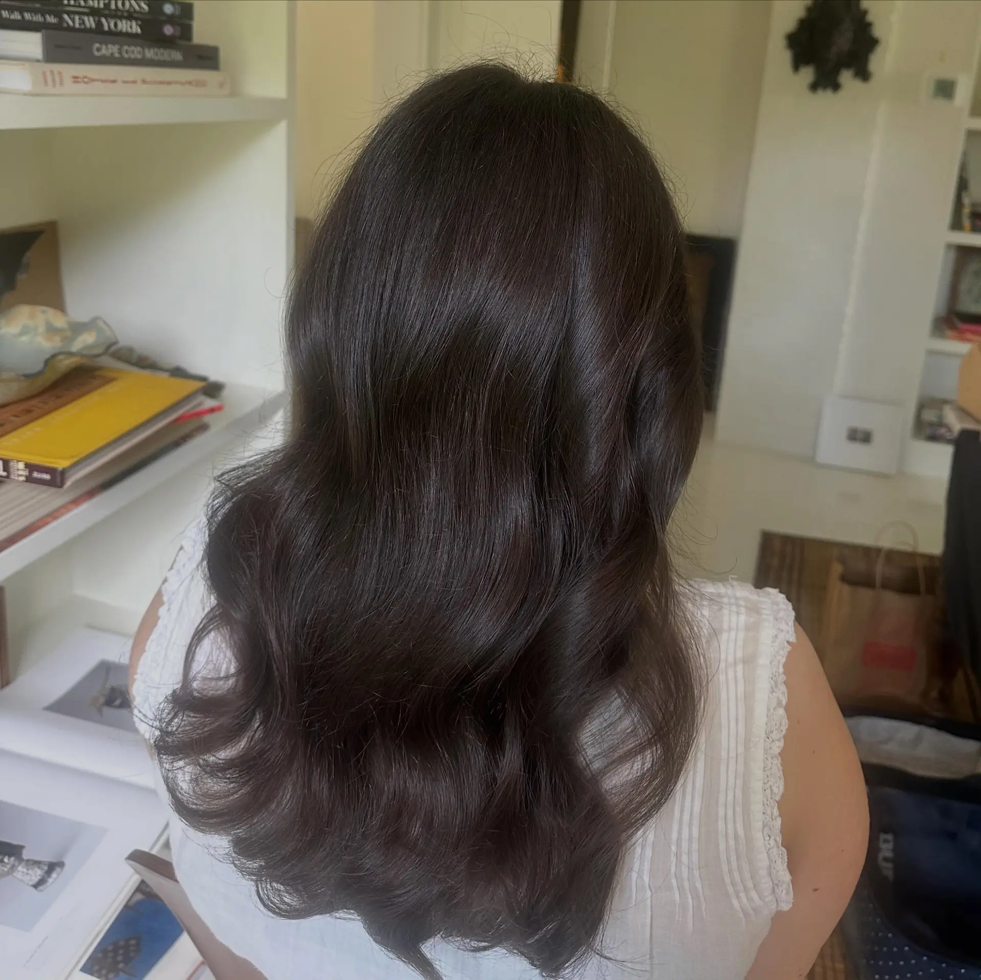 Long dark brown hair styled in soft, glossy waves. 1