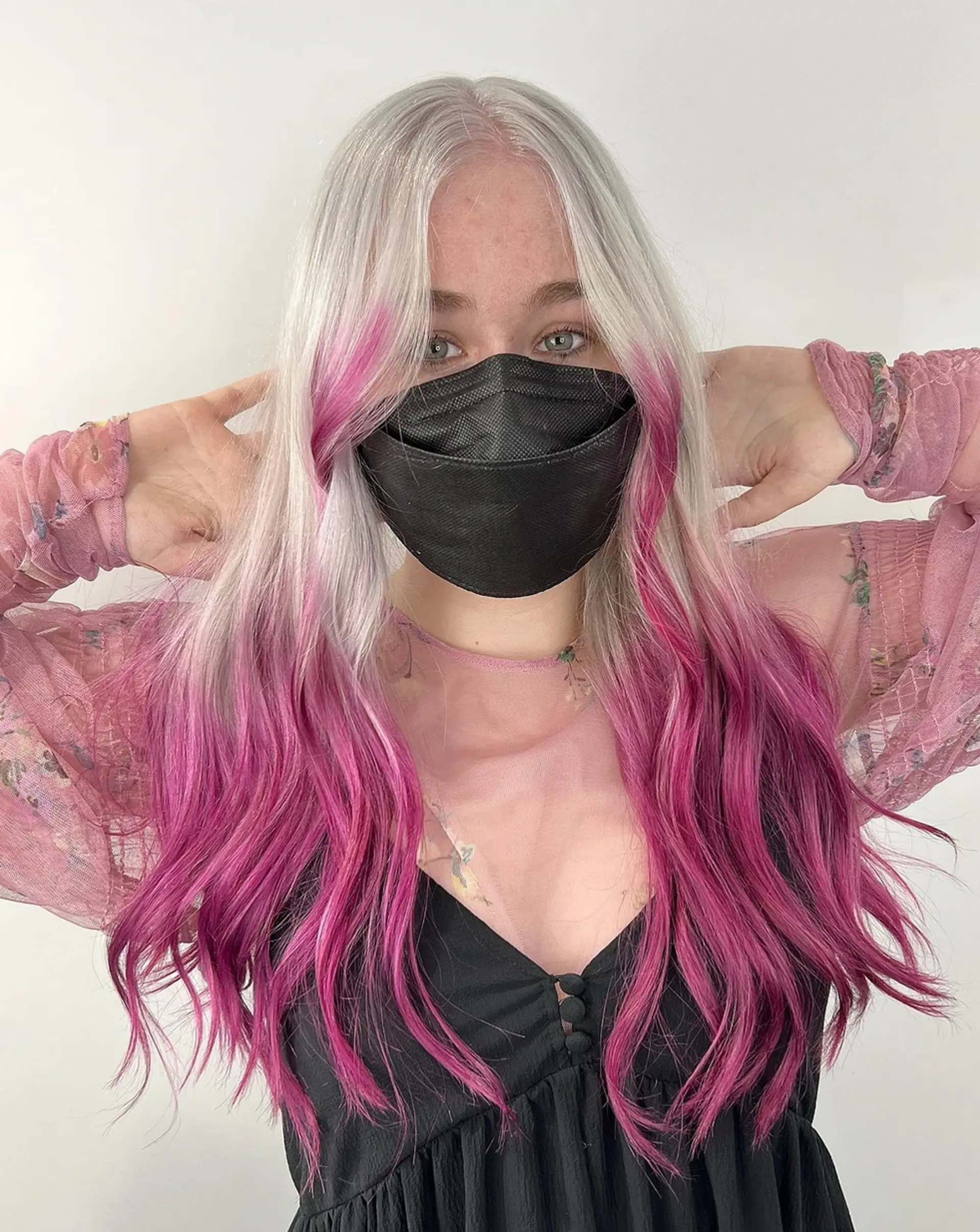 Long, wavy hair with a platinum blonde to magenta ombre, featuring a center parting and soft, natural waves. 1