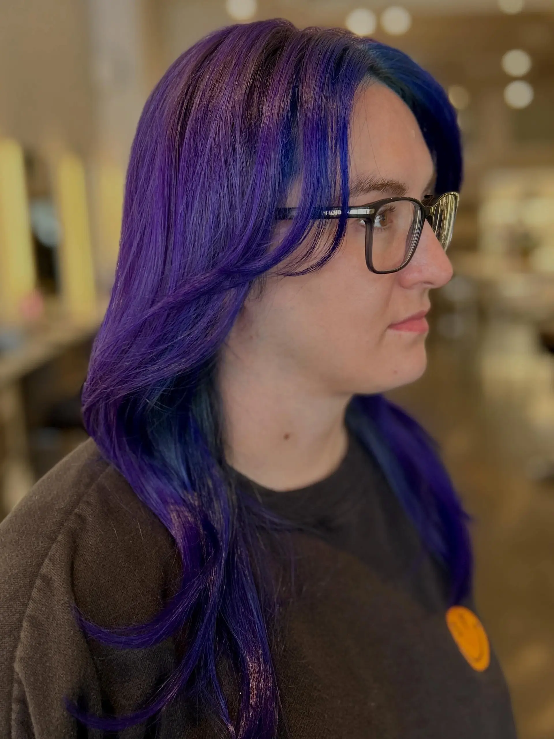 Vibrant creative hair coloring featuring rich royal purple and cobalt blue undertones, styled with face-framing curtain bangs and gentle layers. 1