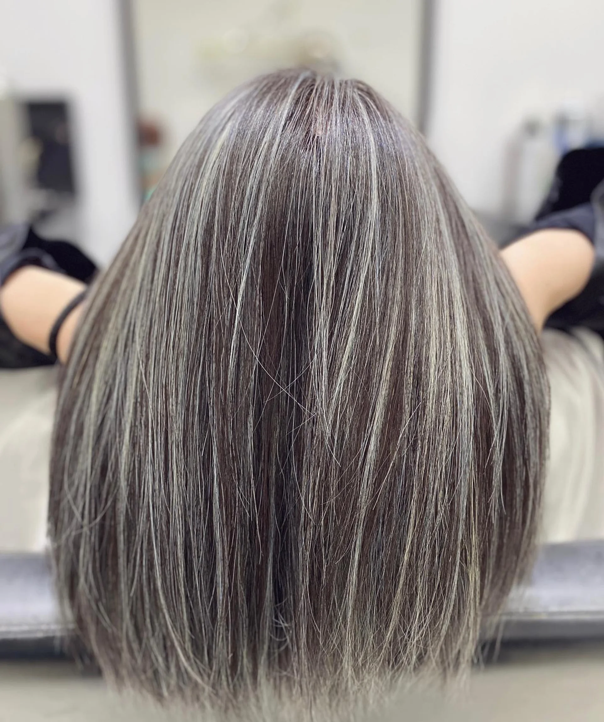 A woman with long, wavy hair showcasing a stunning smoky gray balayage, a key 2025 hair trend for blending natural silver tones. - Preview 3