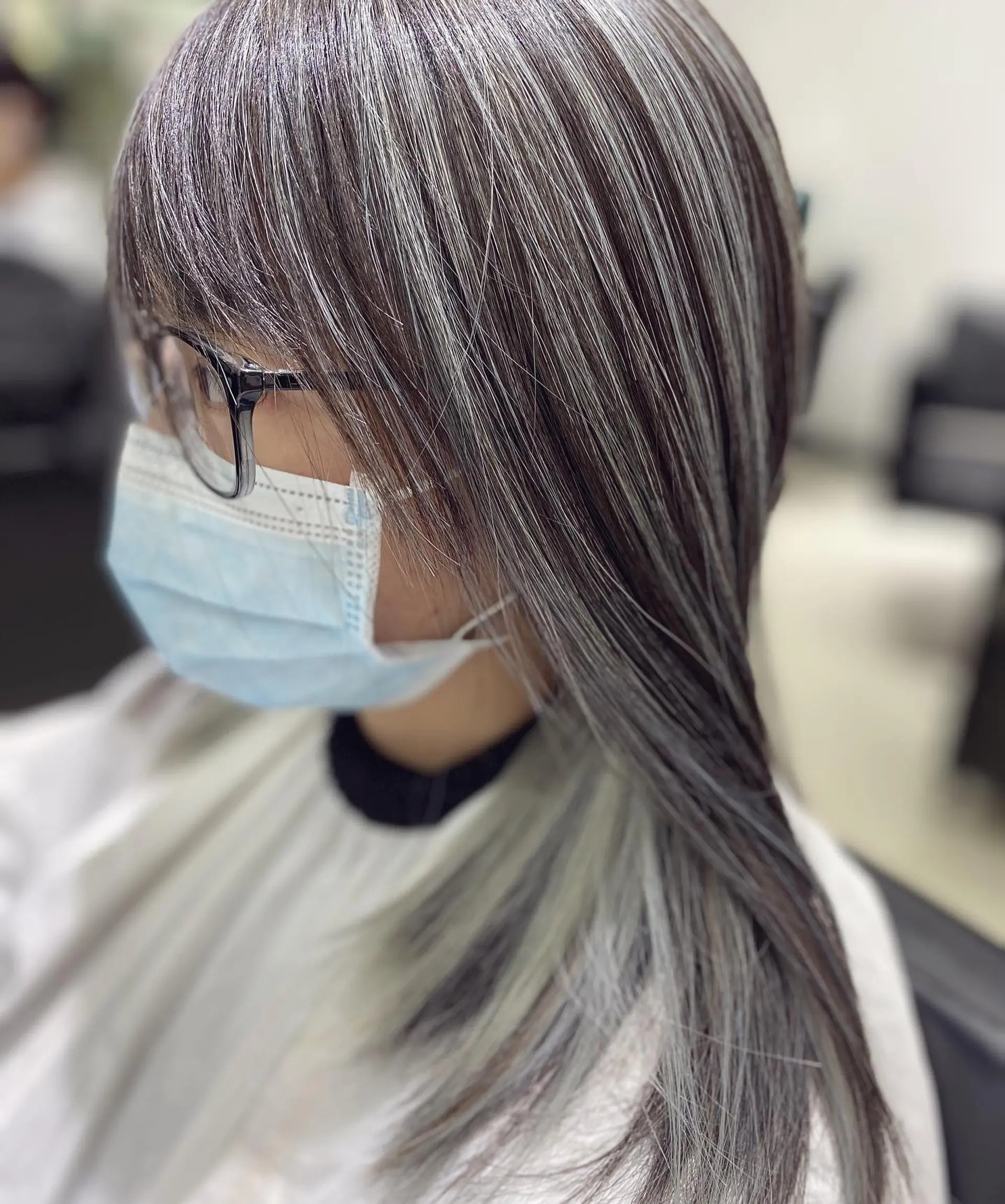 This hairstyle features medium-length, straight brunette hair with strategically placed silver highlights creating a subtle, modern look. 2