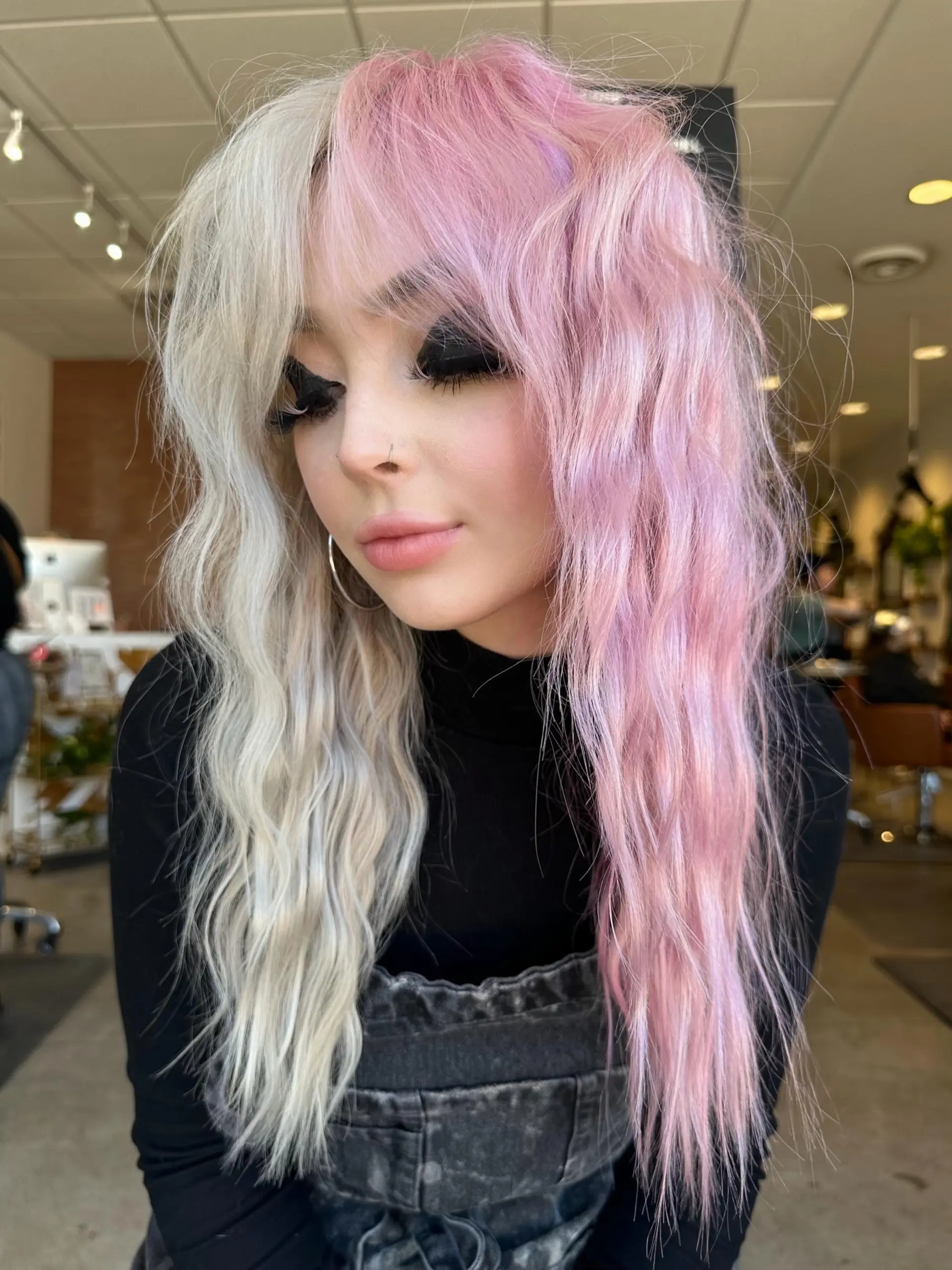 Split-dyed long hair featuring icy platinum blonde on one side and soft pastel pink on the other, styled into textured waves with face-framing fringe. 1