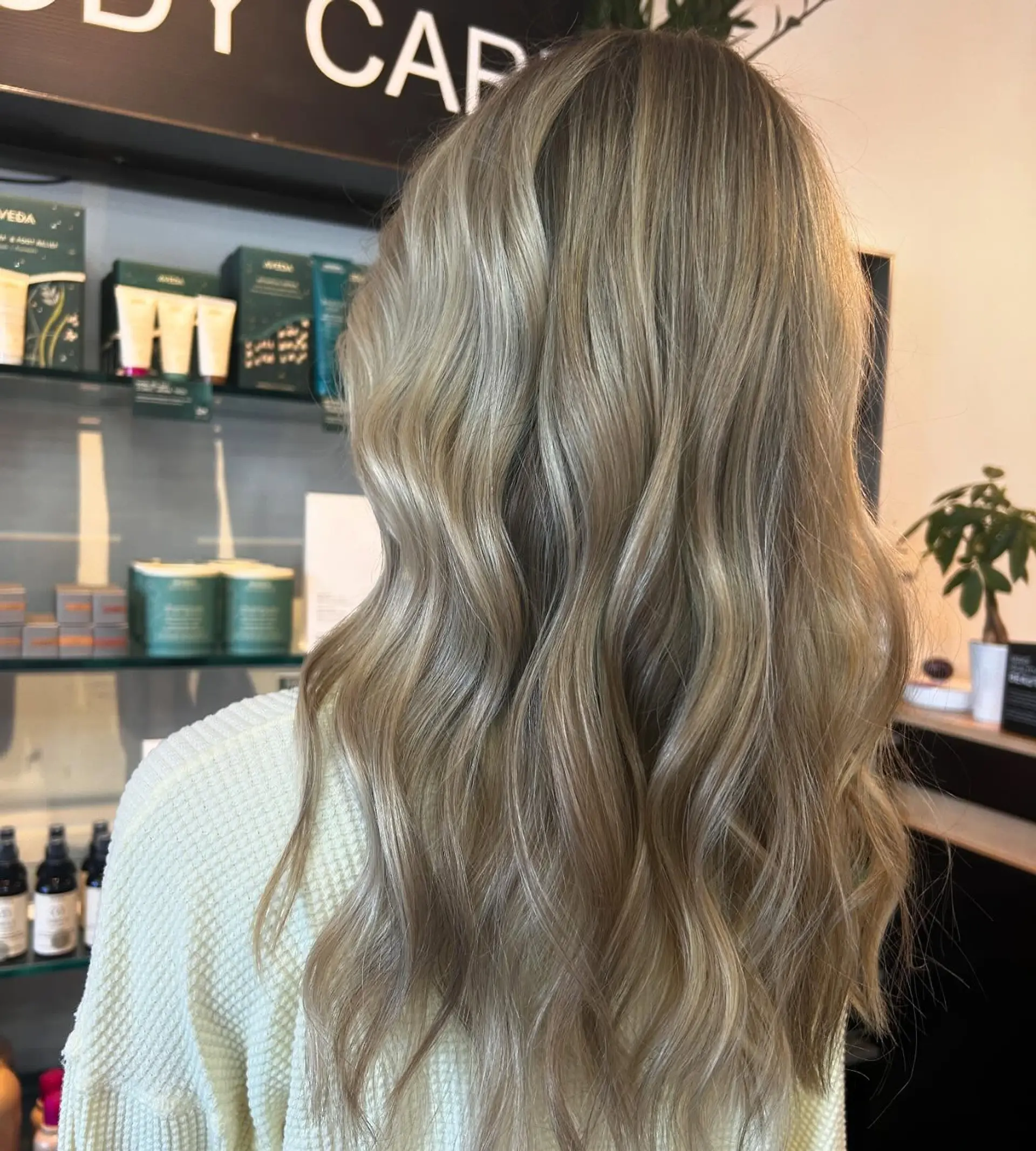 Long dimensional blonde hair styled into soft, beachy waves cascading down the back. 1
