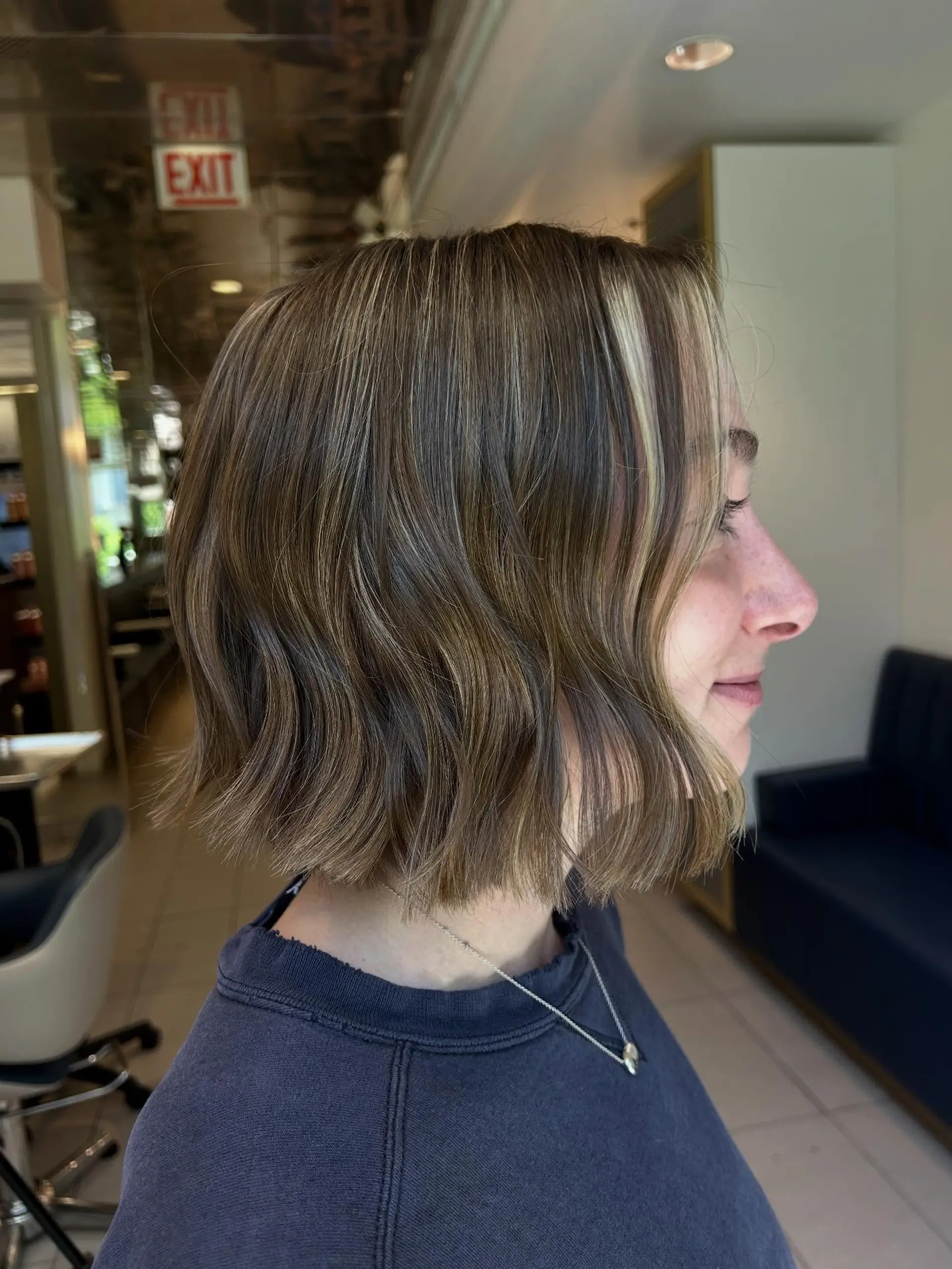 A blunt chin-to-neck length bob styled with relaxed bends and dimensional blonde highlights. 1