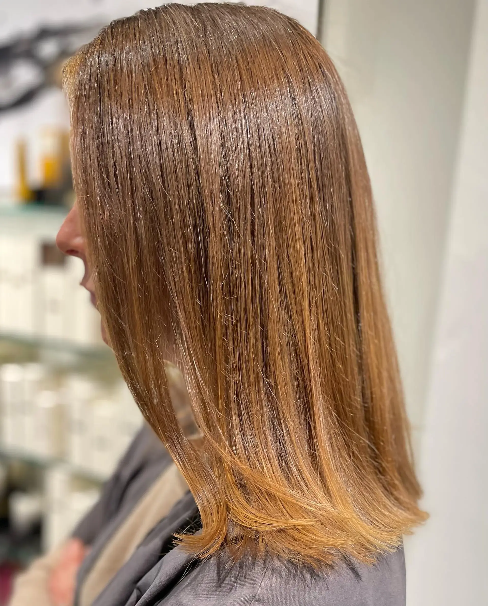 Shoulder-length straight lob haircut enriched with warm honey-toned balayage highlights and a shiny finish. 1