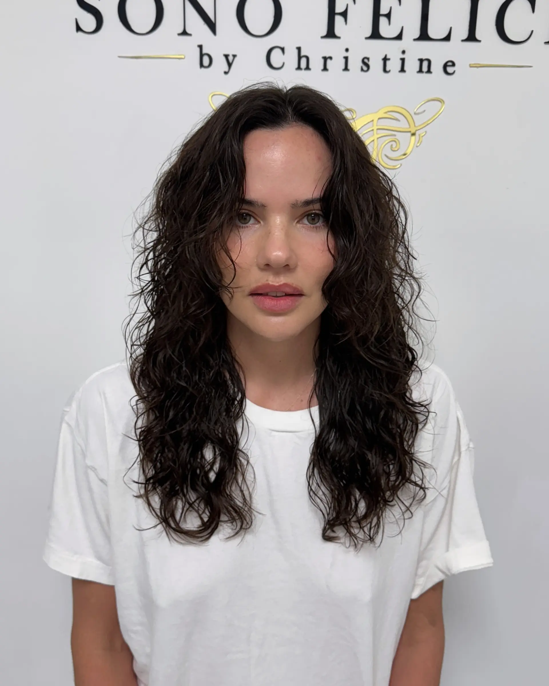 This hairstyle features natural, textured waves that fall to a medium length, enhancing the hair's natural movement and creating a relaxed yet polished look. 1