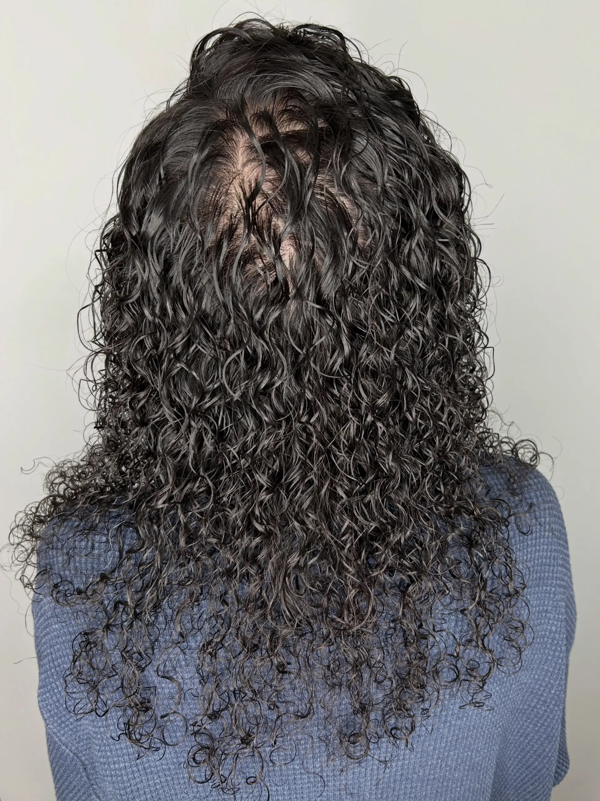 Medium-length dark hair styled into tight, defined spiral perm curls with a glossy finish. 1