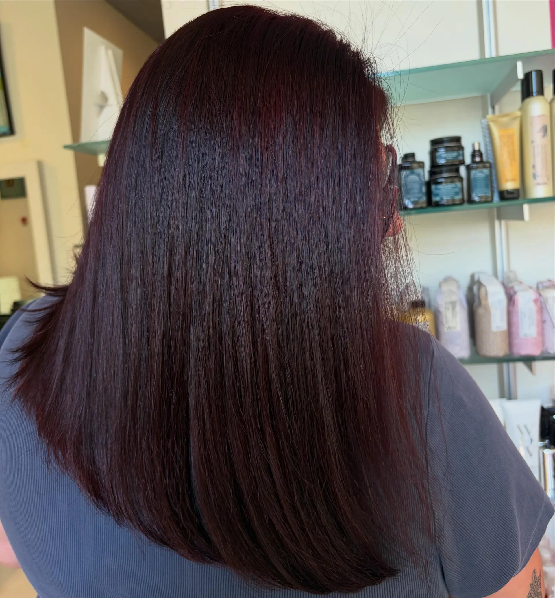 A sleek, smooth blowout featuring deep wine red and rich burgundy undertones on long straight hair. 1