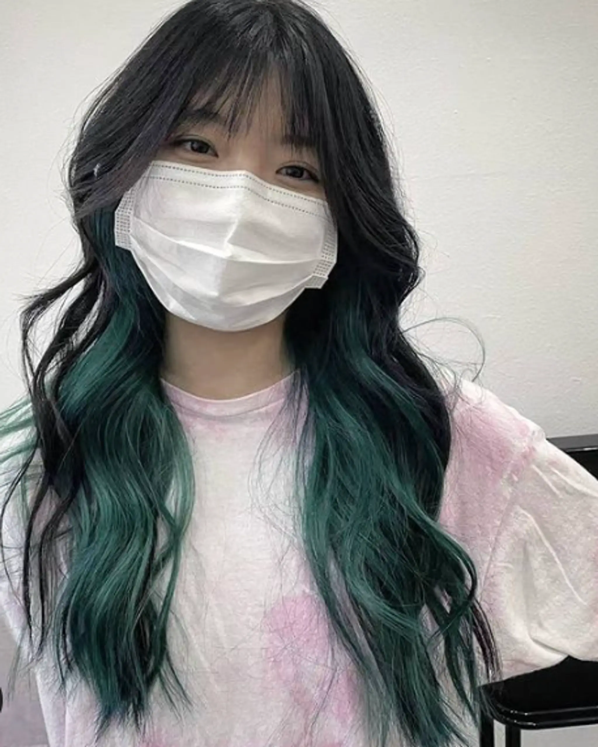 Long, wavy hairstyle with black-to-teal gradient color, face-framing fringe, and textured waves.