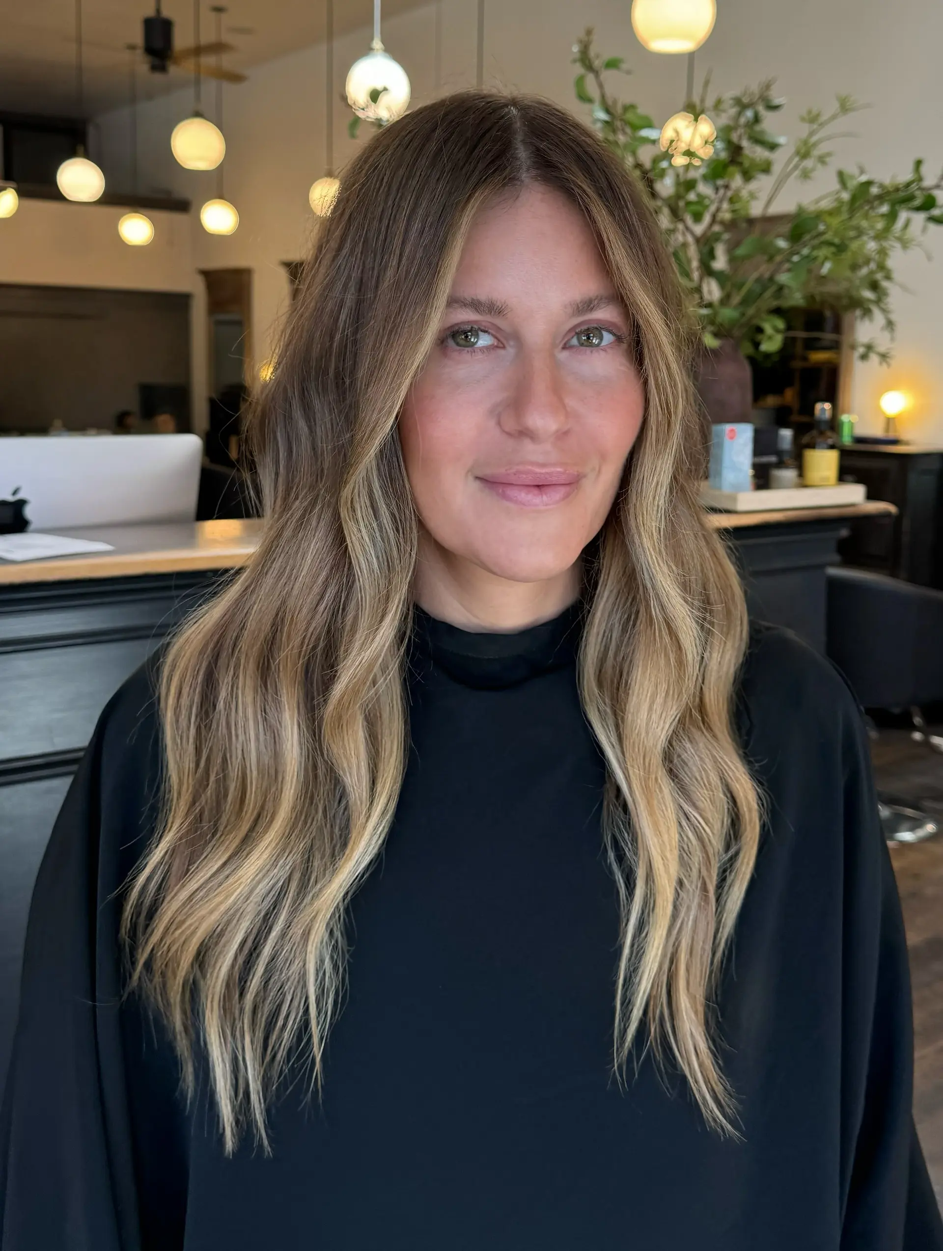 Long center-parted hair styled in soft waves with dimensional bronde highlighting and bright face-framing pieces. 1
