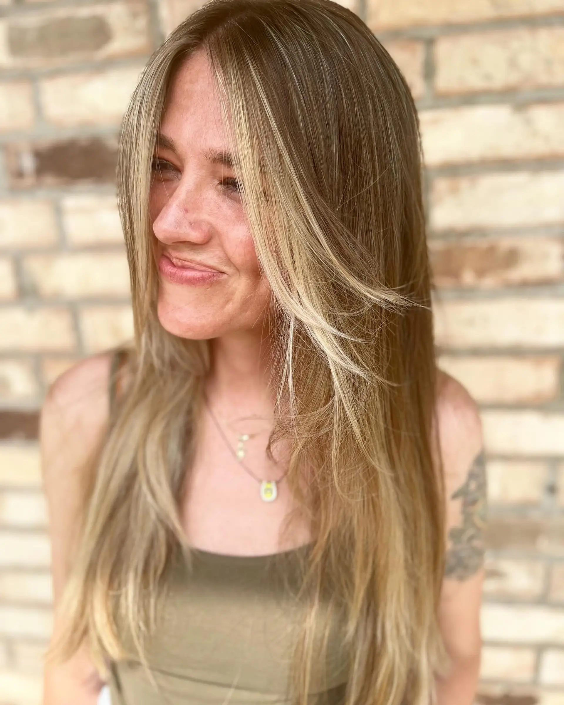 Long, smooth light brown hair featuring bright blonde face-framing money pieces and soft layers. 1