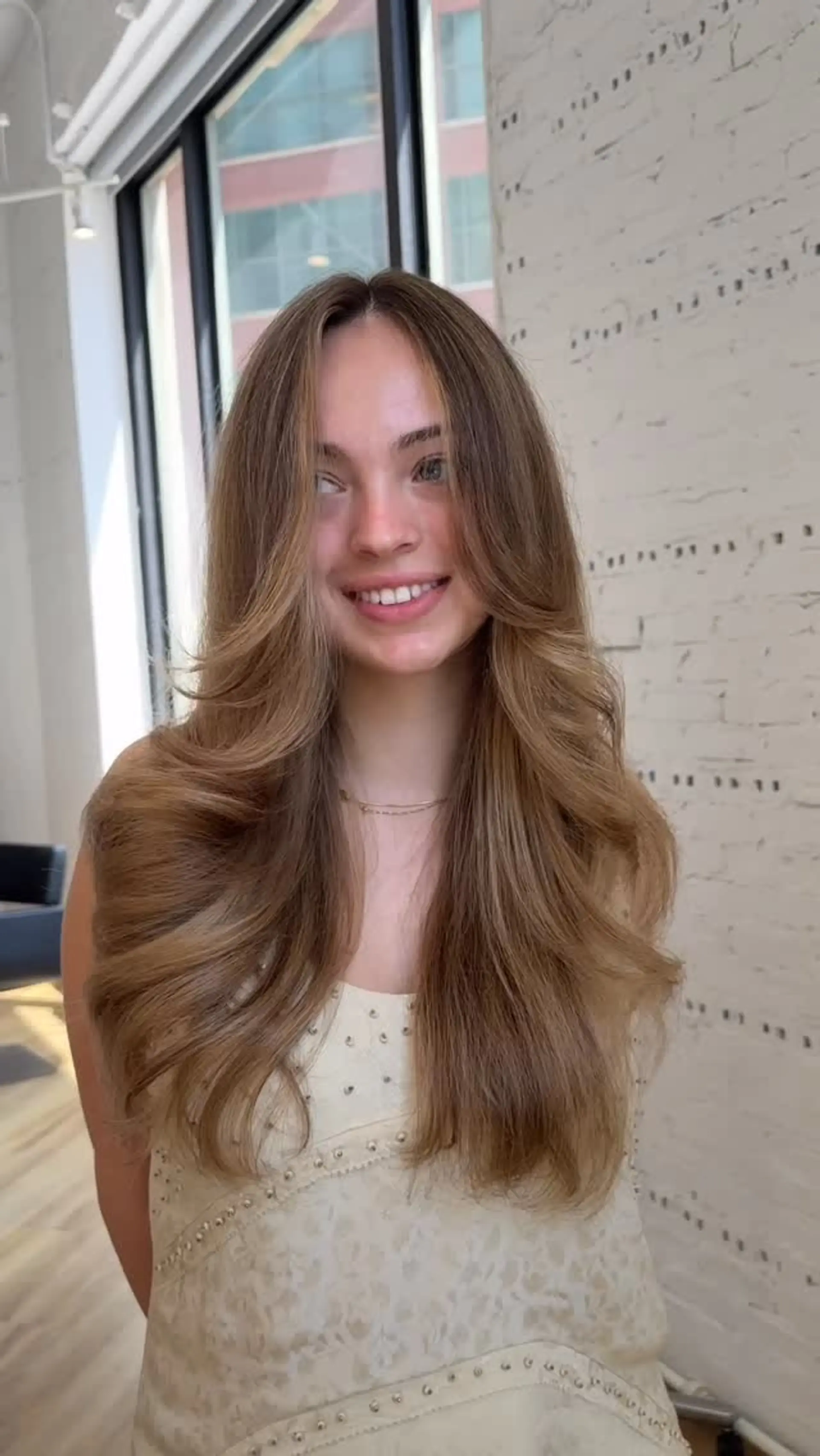 Long layered hair styled with a soft blowout and dimensional bronde balayage featuring face-framing highlights. 1