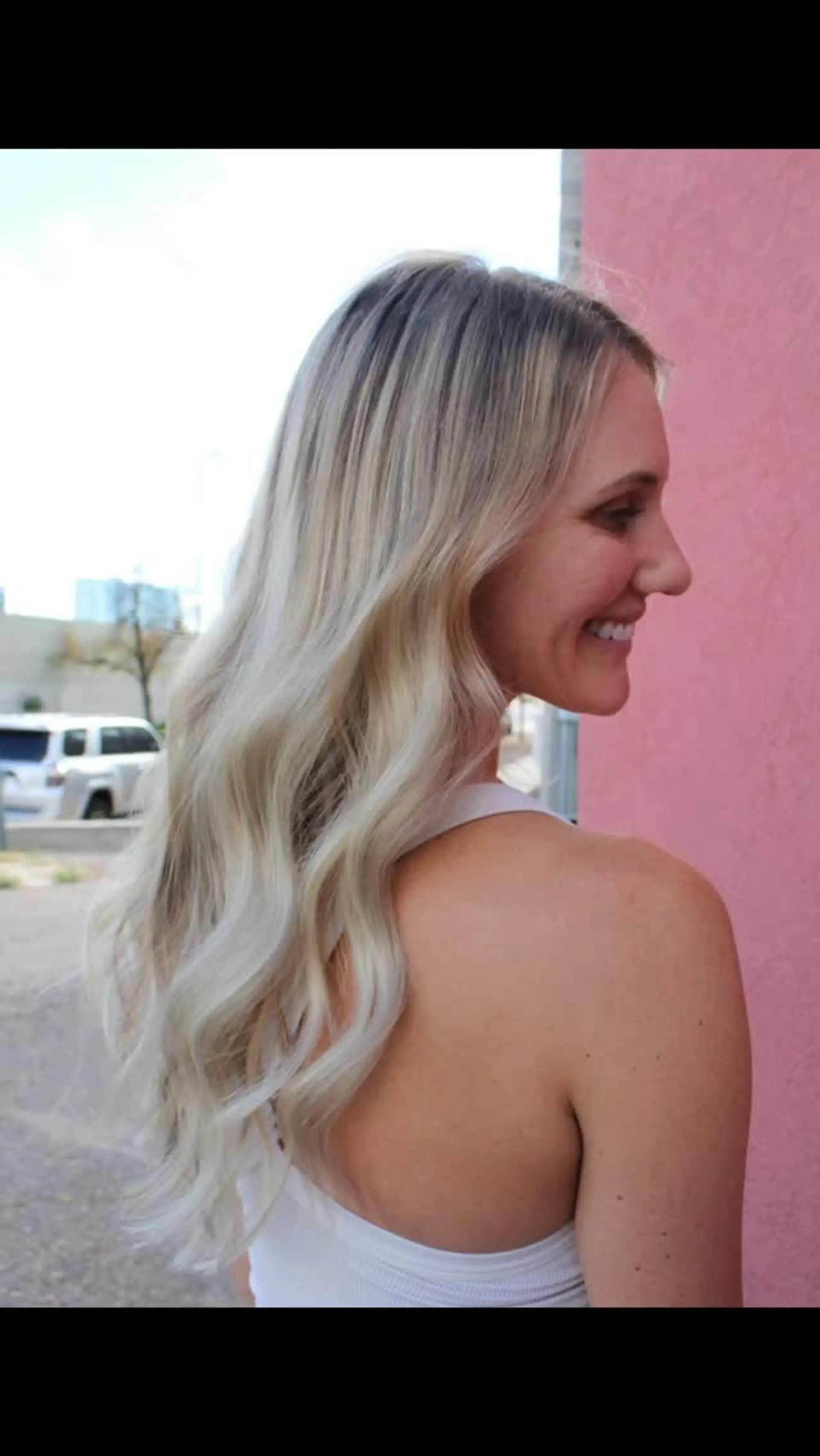 Long lived-in blonde hair styled with soft, cascading waves and a natural shadowed root. 1