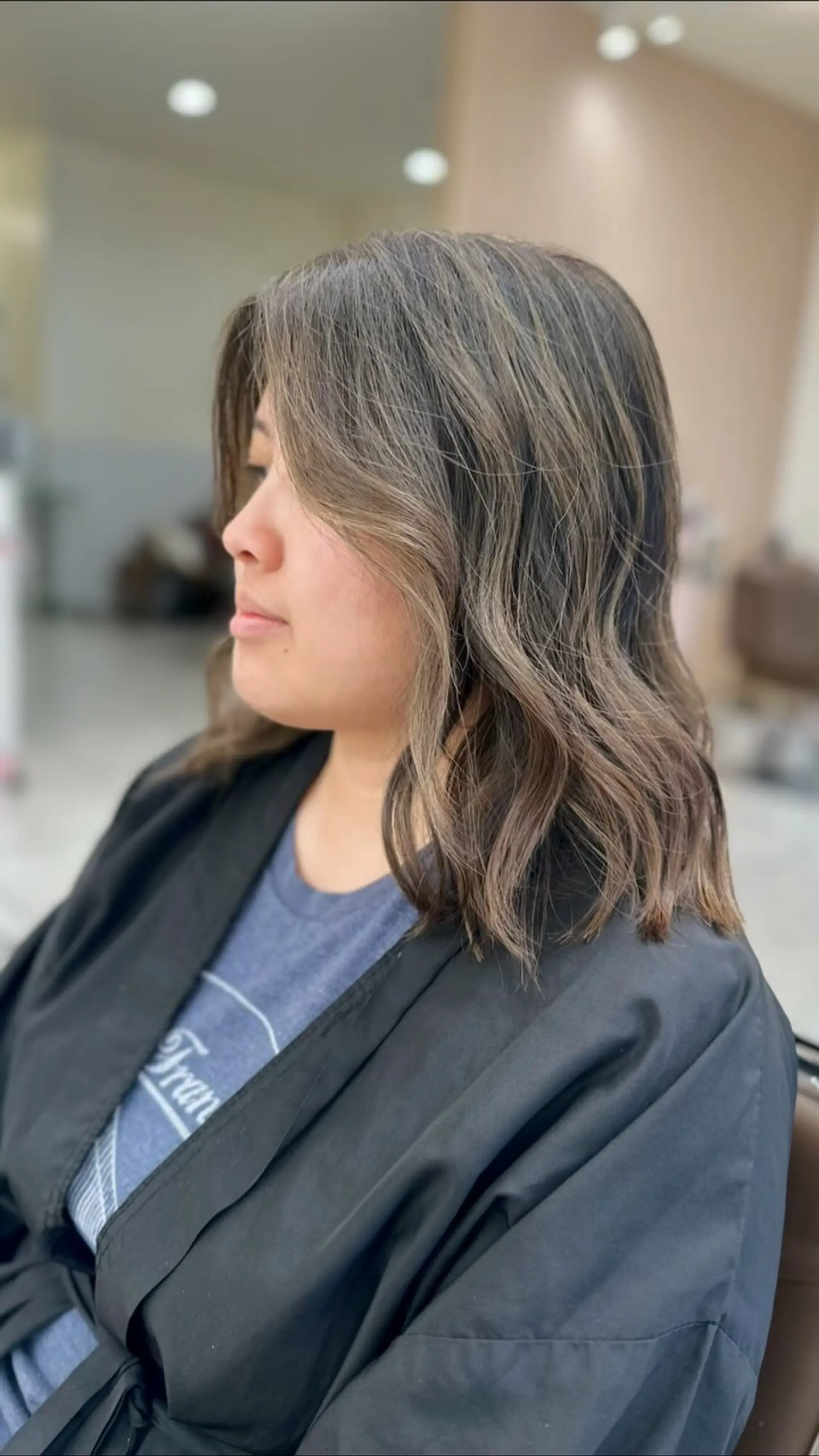 A collarbone-length layered lob featuring dimensional ash brown highlights blended over a deep brunette base, finished with soft waves. 1