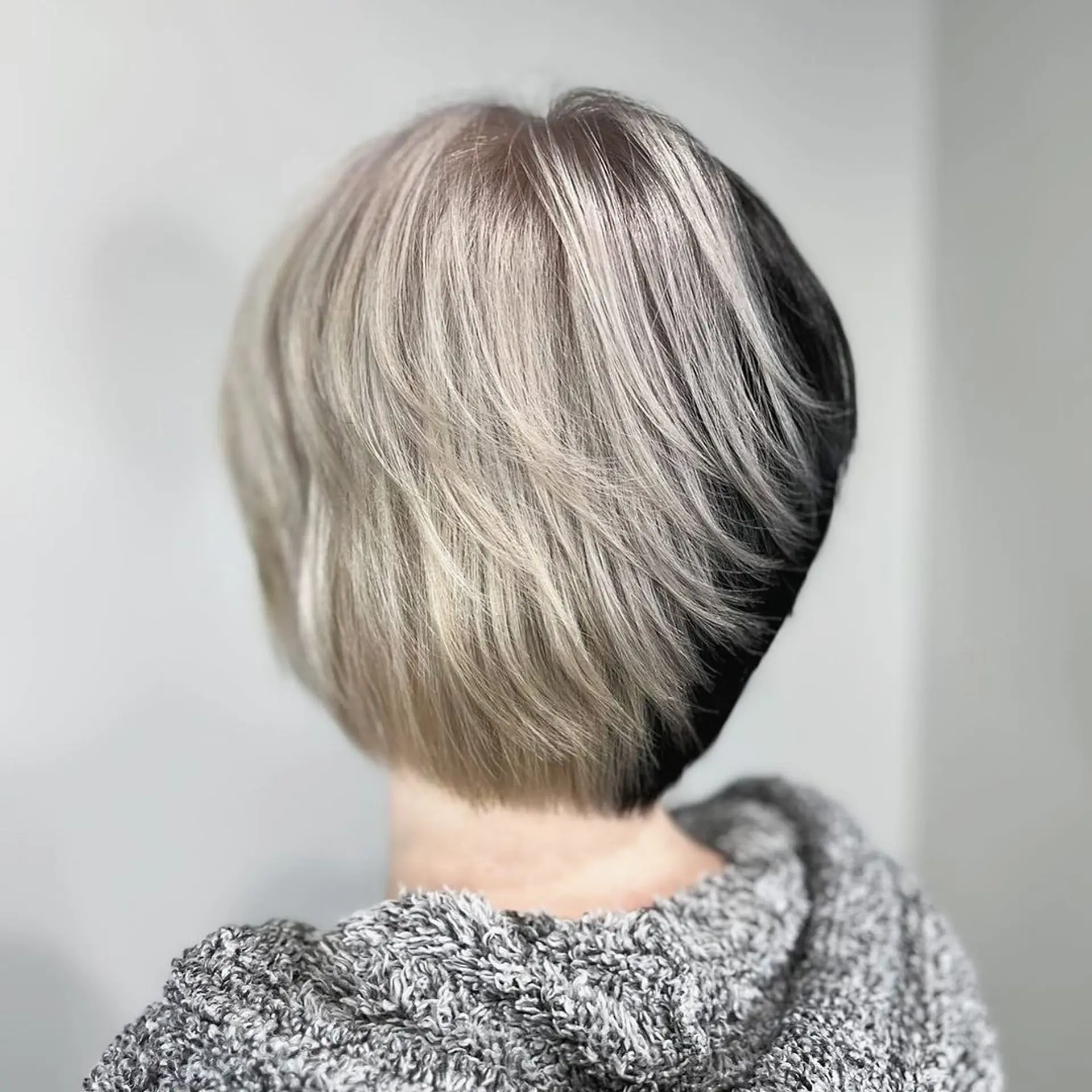 Short, layered hairstyle with straight texture, featuring a two-toned platinum blonde and silver color with black accents, creating an asymmetrical look.
Stylist - @xcellent_jason 1