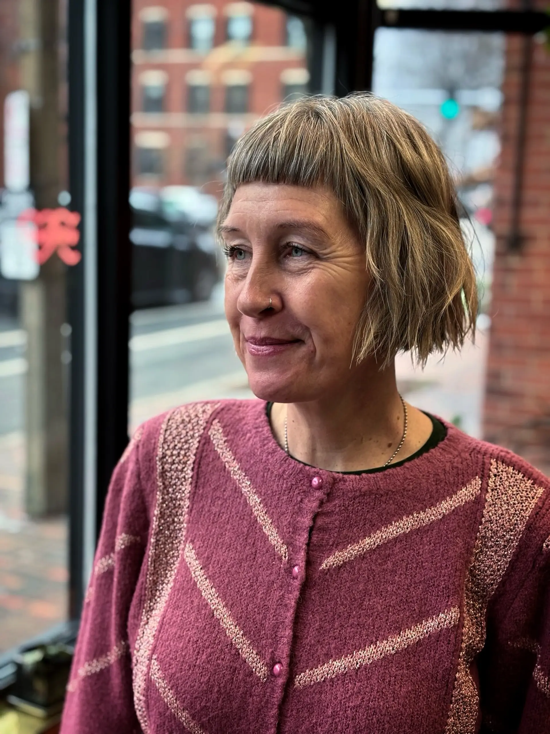 A textured chin-length bob styled with blunt micro bangs and subtle natural wave. 1