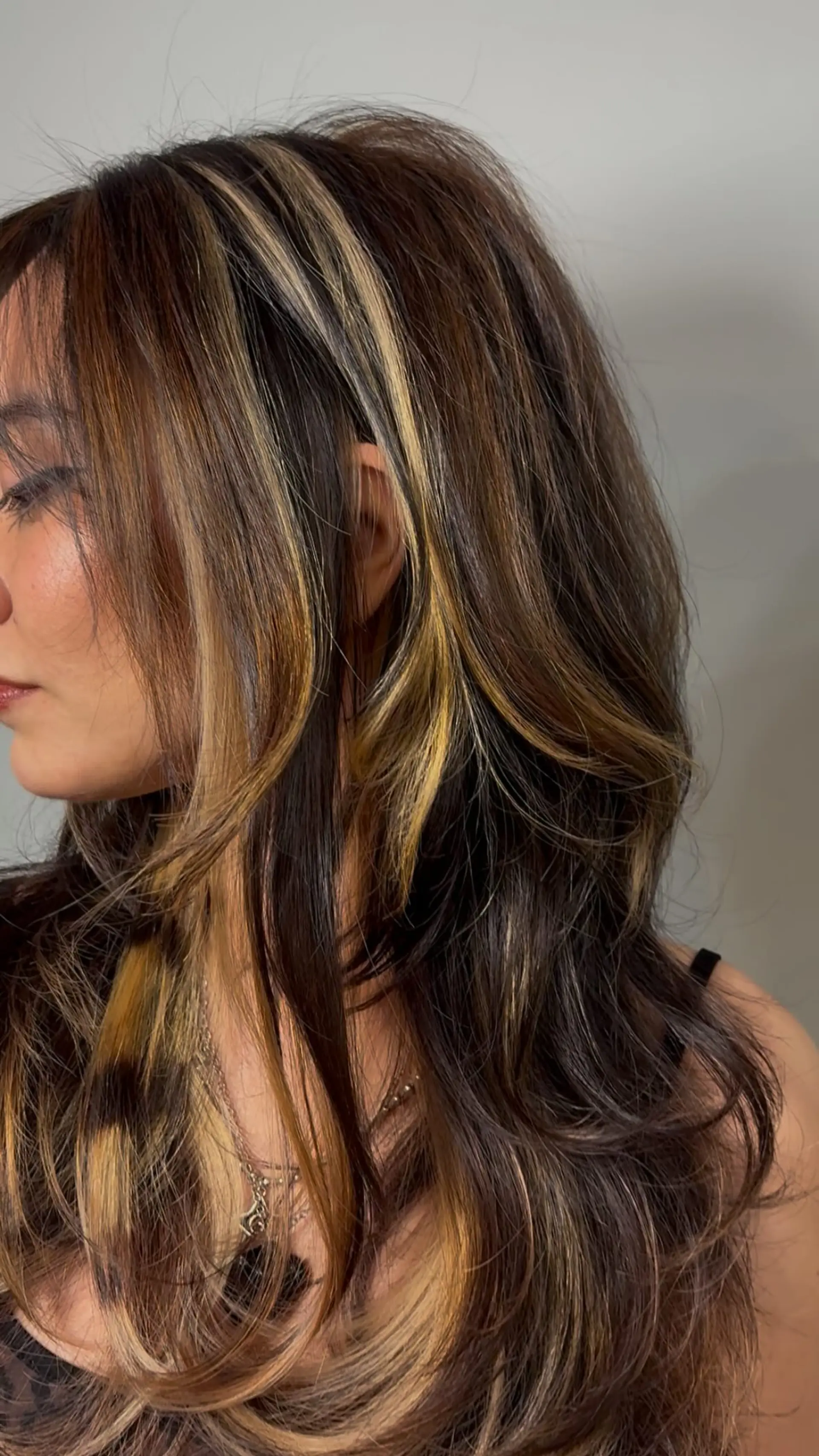 Long, layered dark brown hair styled with soft, voluminous waves and bold calico-style chunky highlights. 1