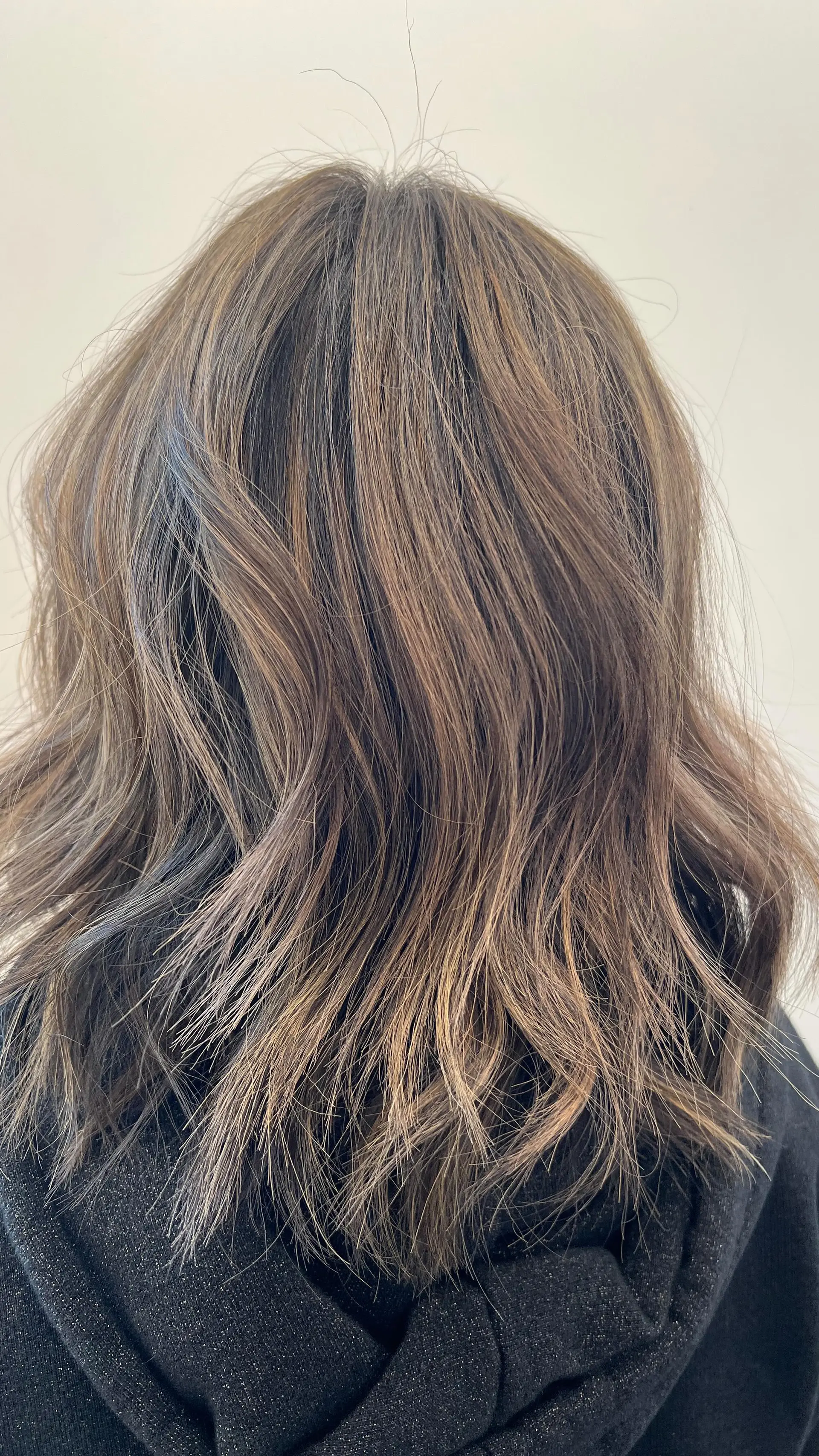 A textured shoulder-length haircut styled in relaxed waves with cool-toned balayage highlights. 1