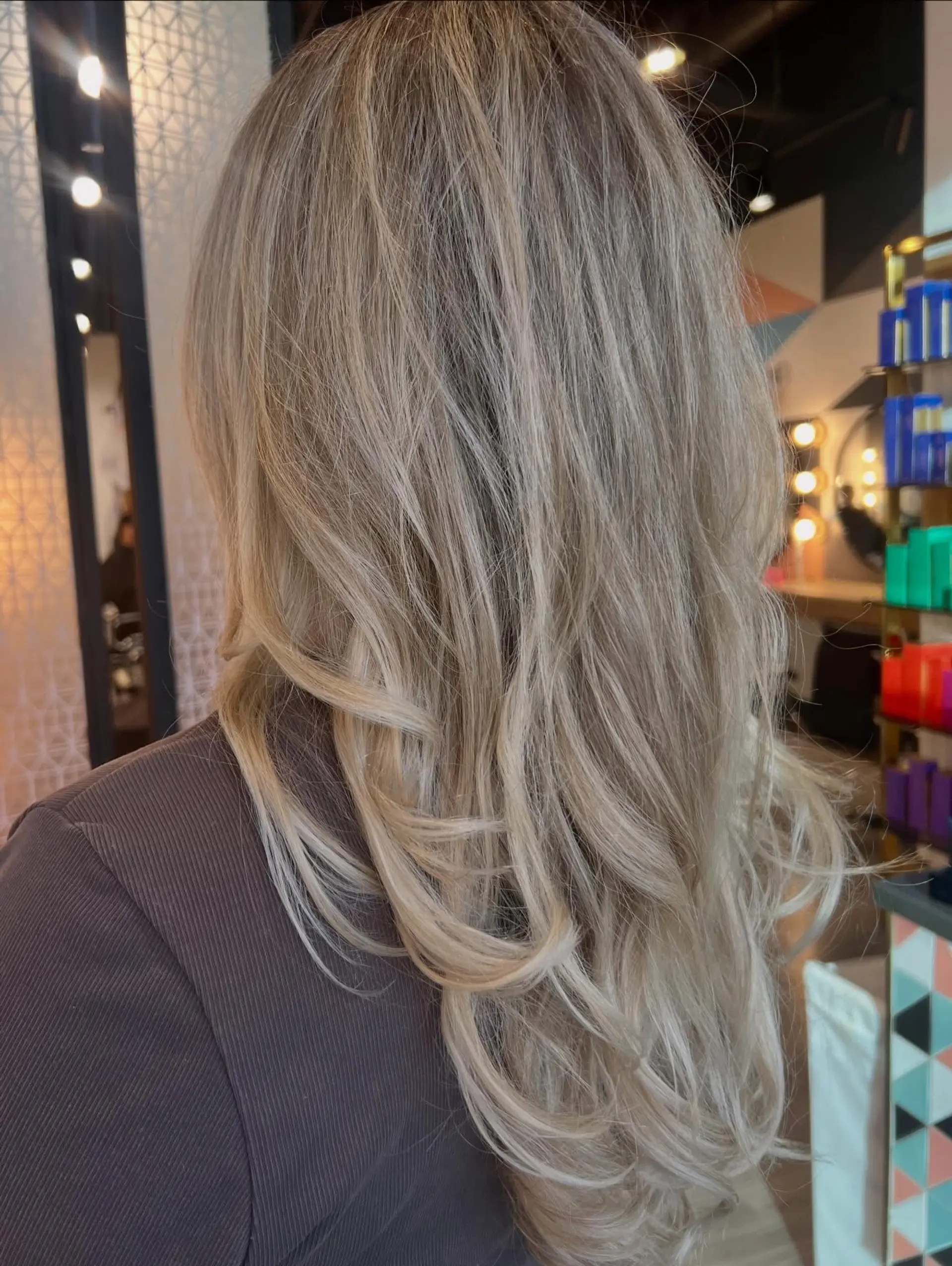 Long cashmere ash blonde hair cut in soft layers with swept, curled ends. 1