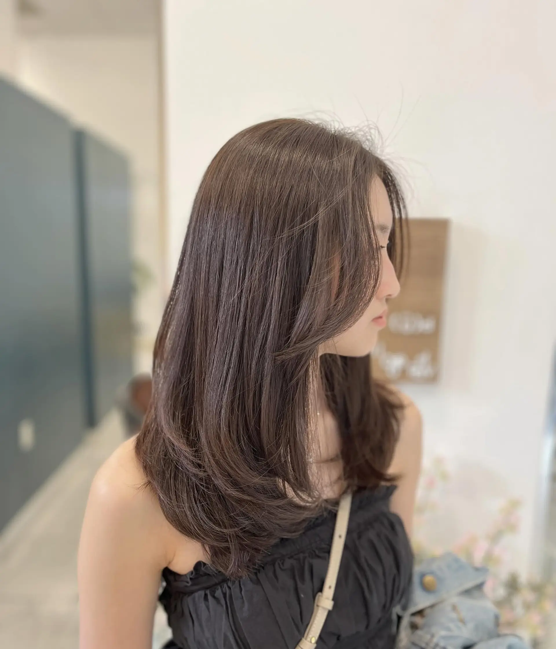 Medium-length layered brunette hair with soft inward curved ends and delicate face-framing curtain bangs. 1