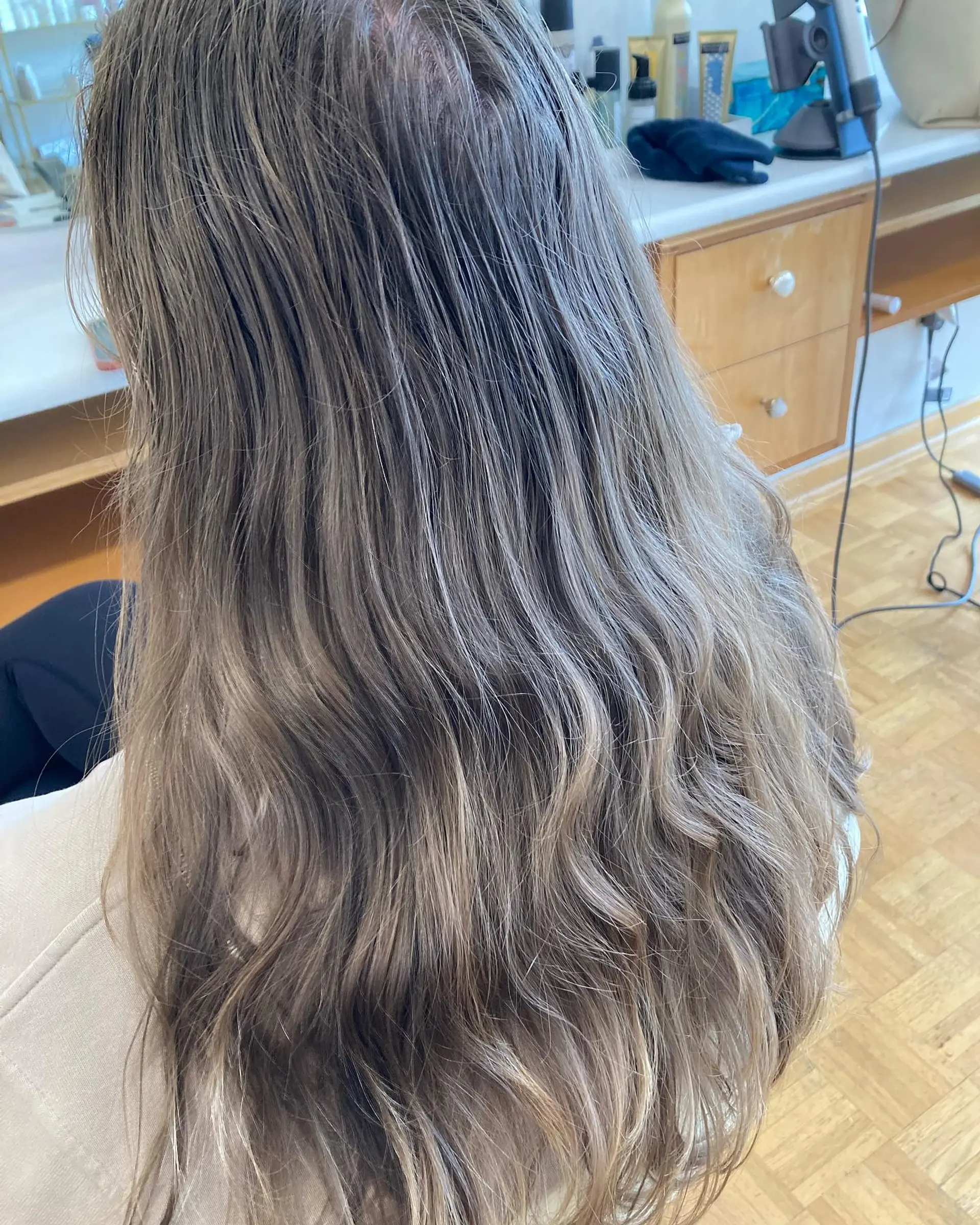 Long, gently waved hair highlighted with cool ash blonde tones seamlessly blended into a natural brown base. 1