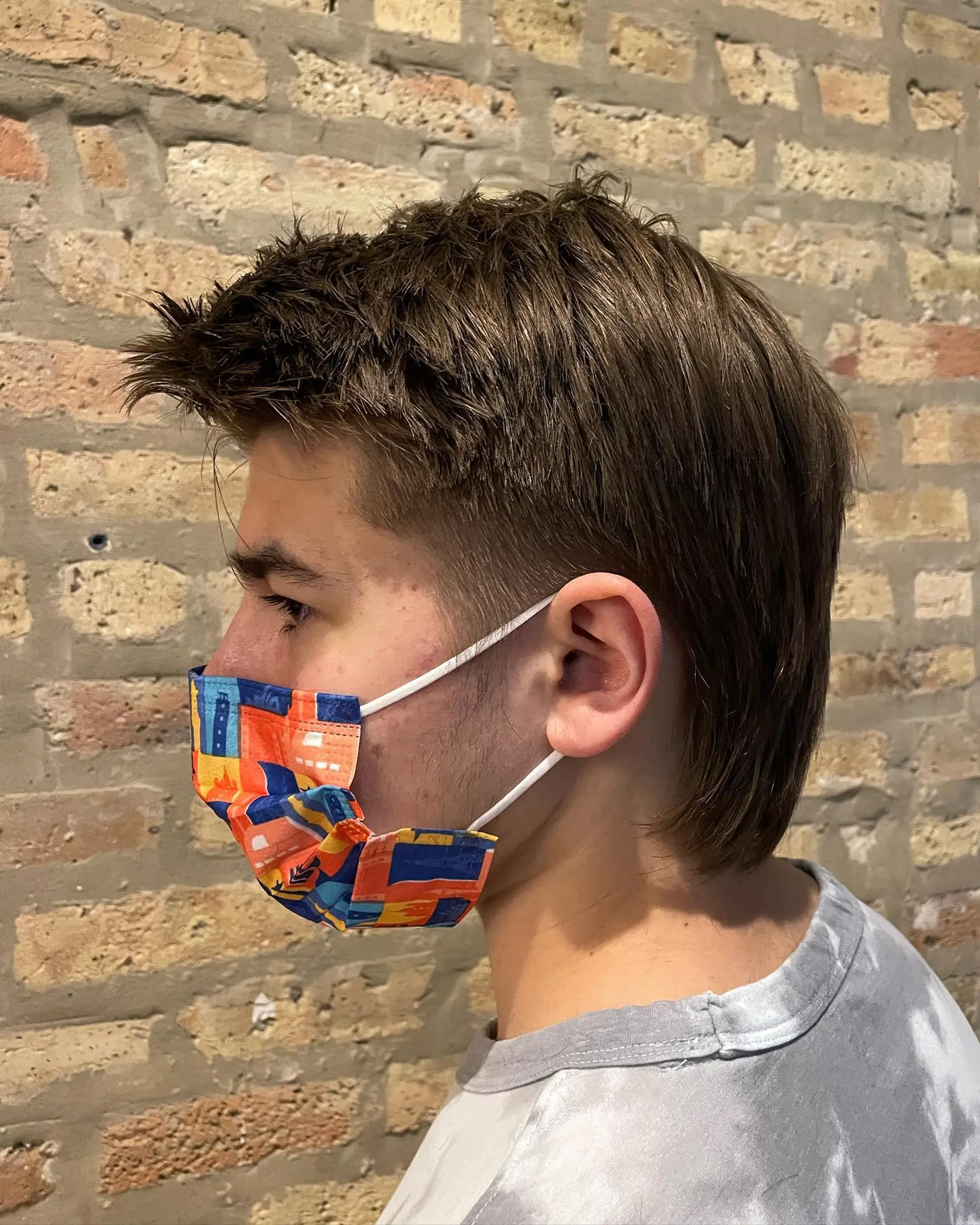 A modern textured mullet with short, piecey hair on top, clean faded temples around the ears, and longer straight lengths running down the nape. 1