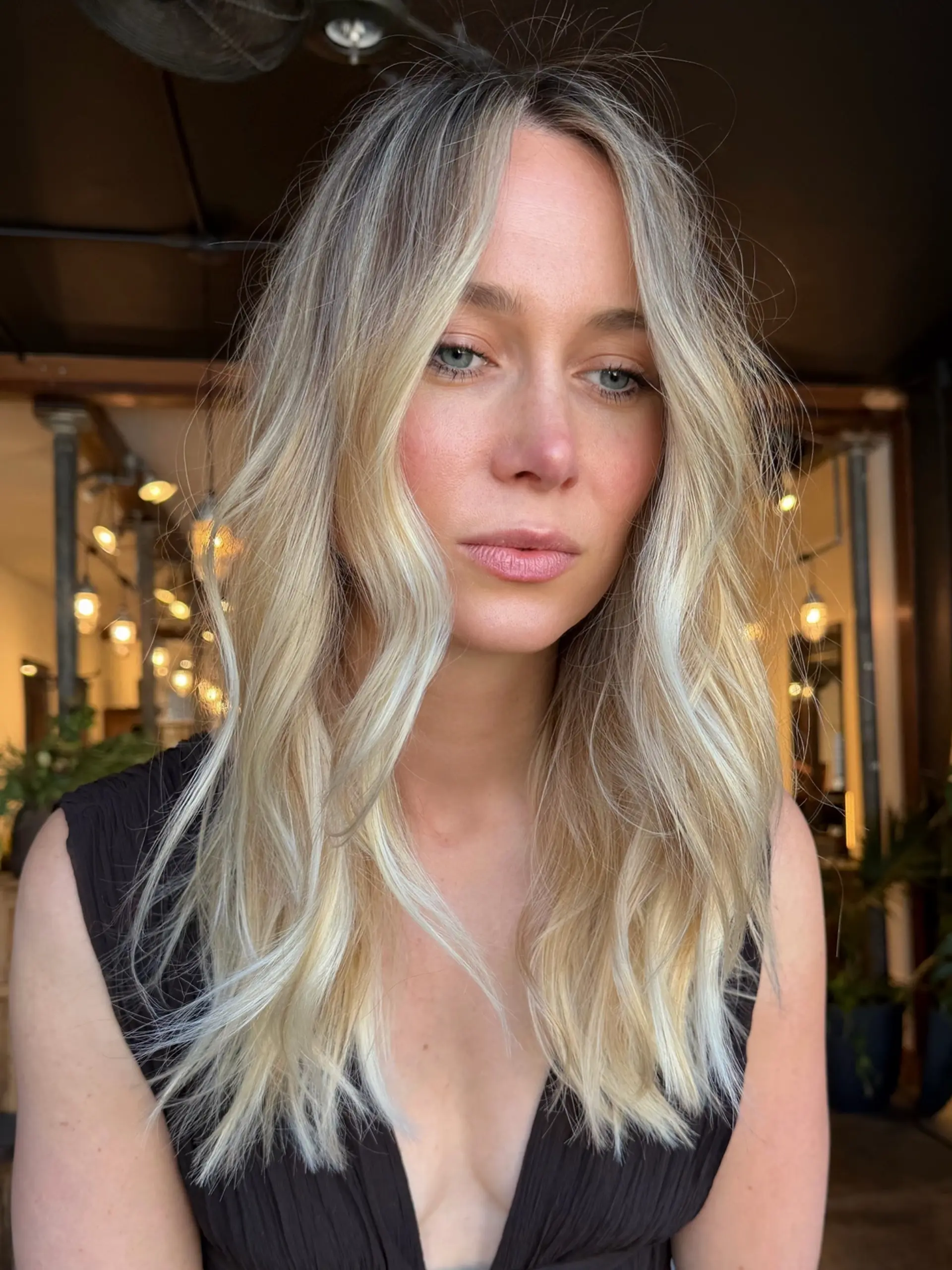 Long dimensional blonde hair styled in effortless, undone waves with a soft middle part and bright face-framing pieces. 1