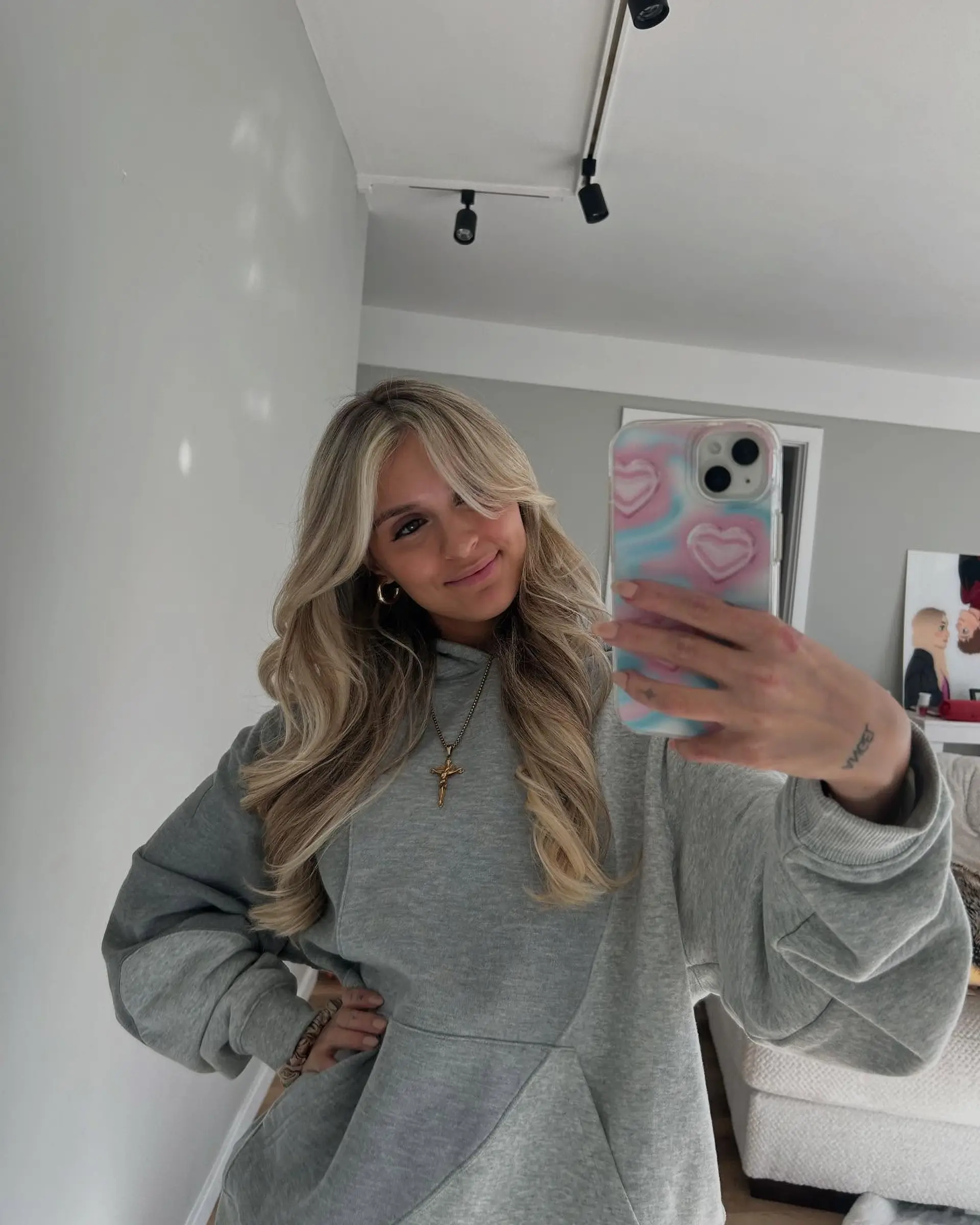 Long dimensional blonde hair styled in bouncy waves with curtain bangs. 1