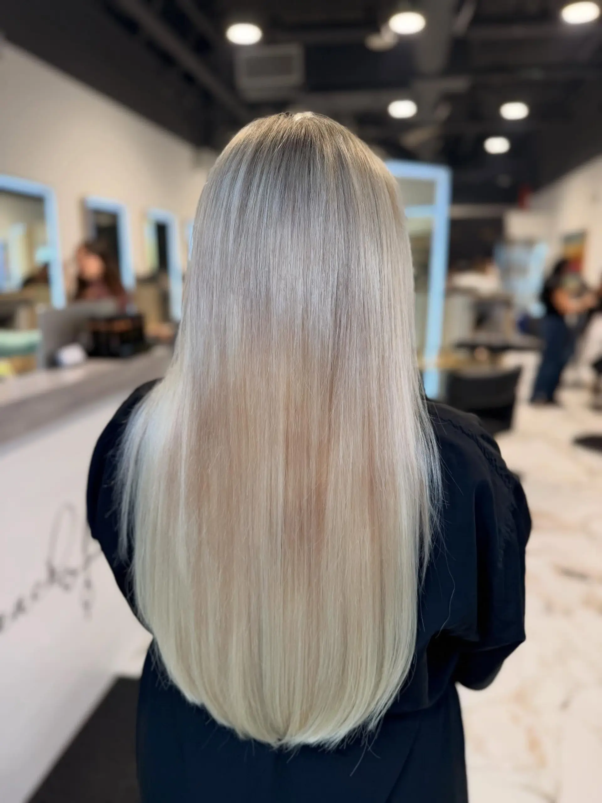 Long, sleek platinum blonde hair styled pin-straight with seamless fullness and a soft U-shaped hemline. 1