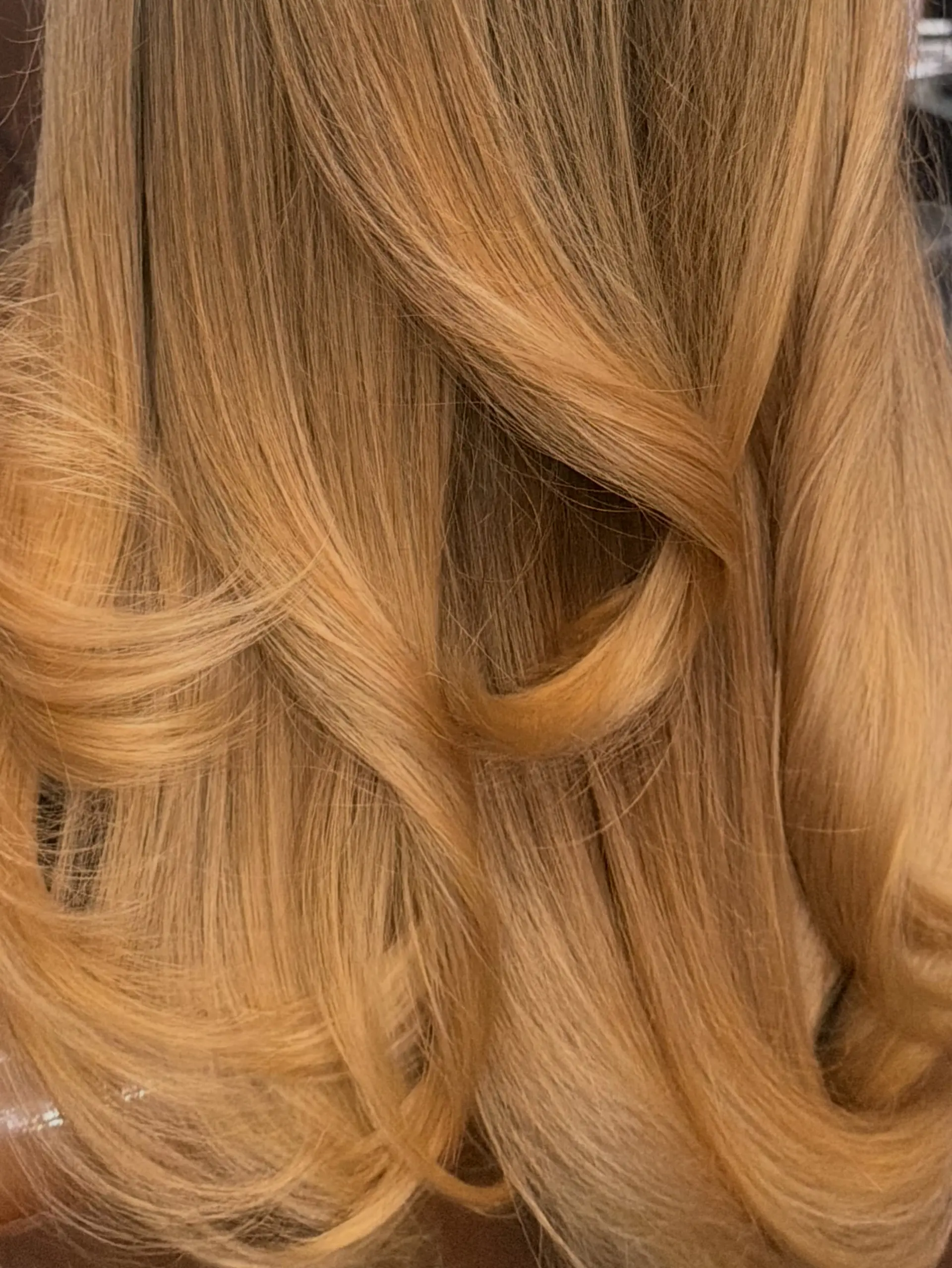 Warm honey blonde hair styled with smooth, layered curves and a polished blowout finish. 1