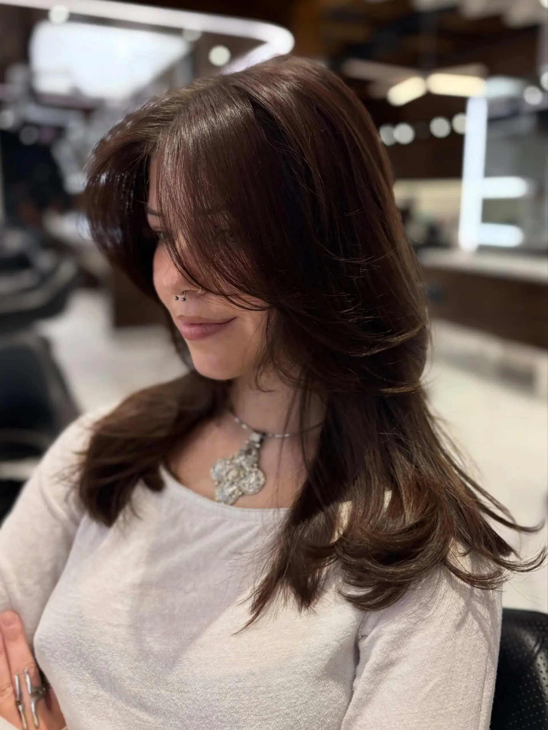 Long chocolate brown haircut featuring sweeping curtain bangs and soft, face-framing layers with a voluminous blowout. 1