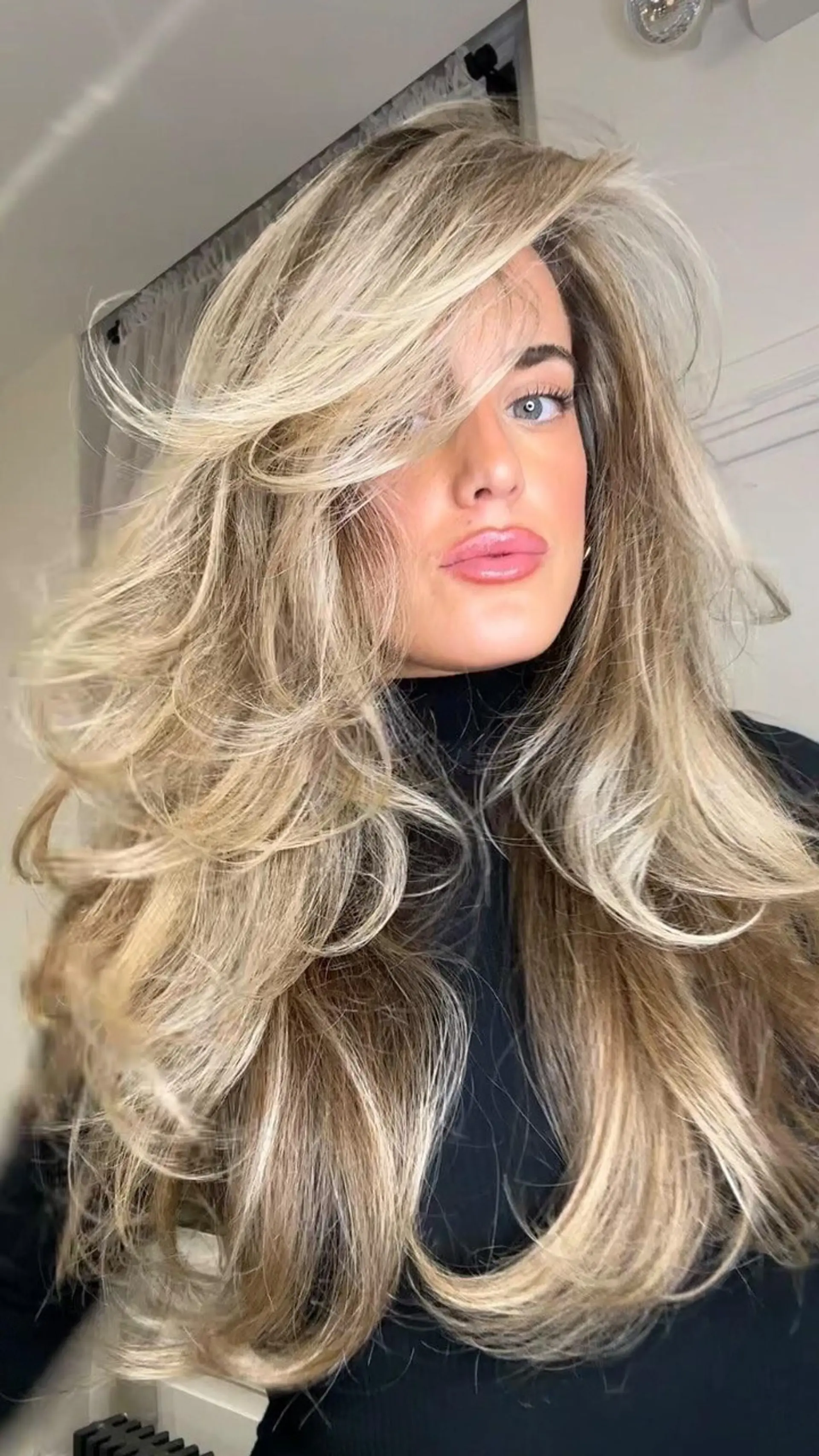 A glamorous, high-volume blowout featuring feathered face-framing layers and fine babylight balayage. 1