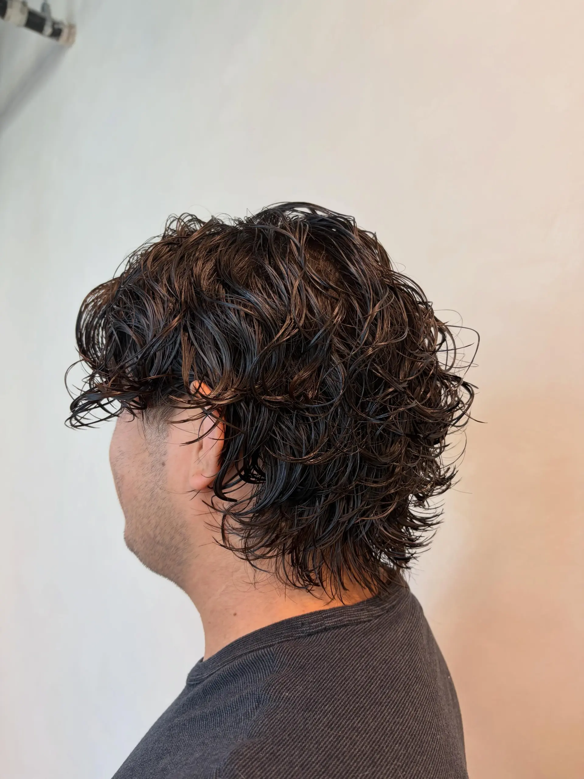 A men's wavy texture perm styled with piecey definition and a natural wet-look finish. 1