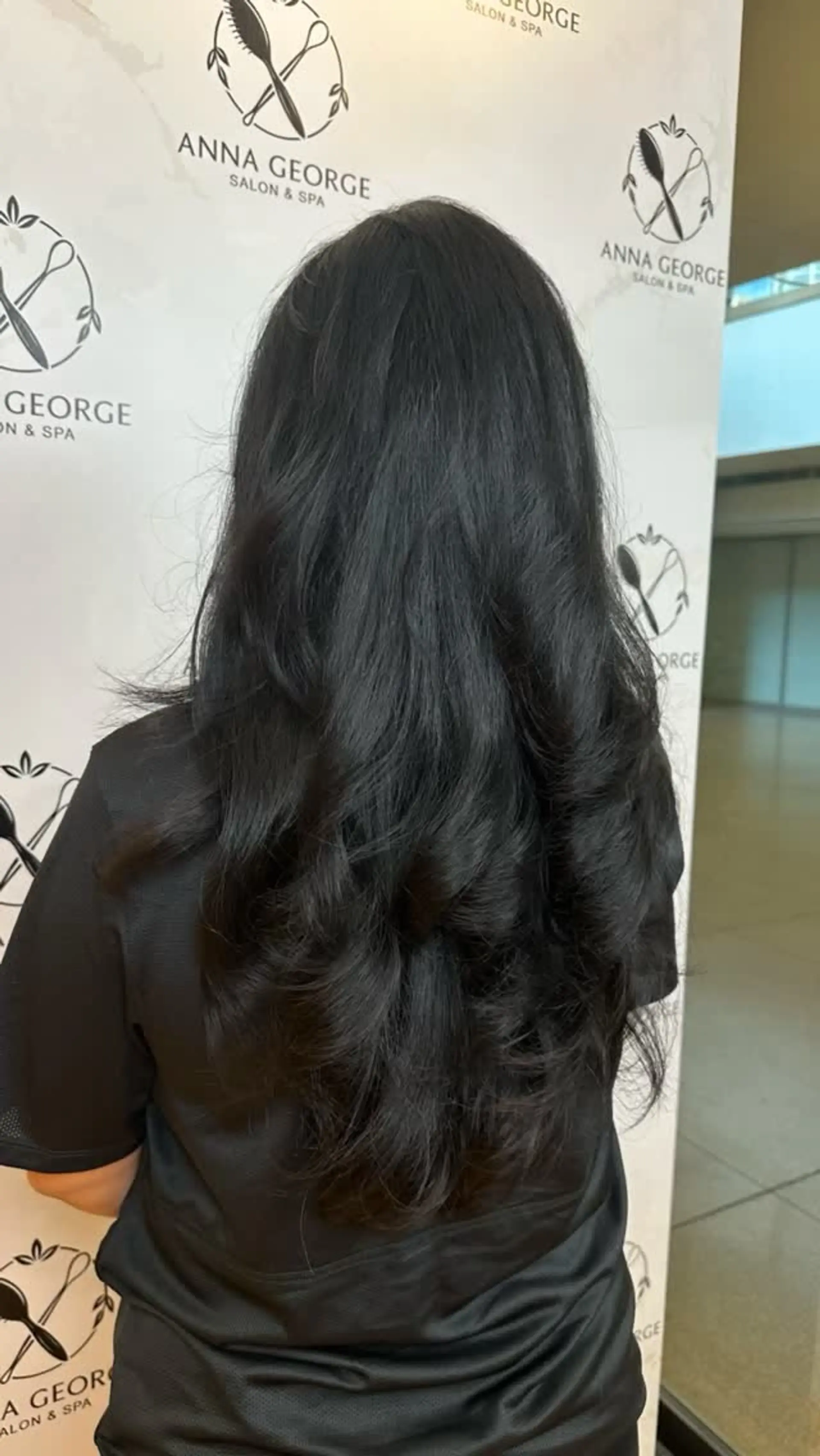 Long jet black hair styled with flowing, voluminous layers and bouncy curled ends. 1