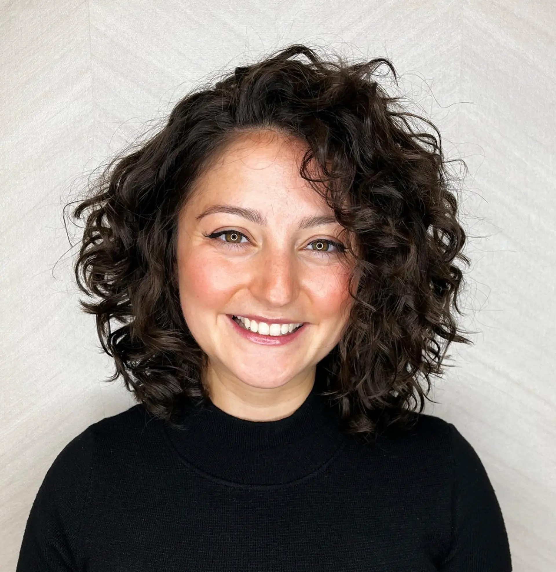 The hairstyle features dark brown, short-length hair with a curly texture characterized by soft, natural ringlets. It has a voluminous, bouncy look with layered cut and loose curls, providing a glossy finish.

Cut and style by @juliamannino_hair 1