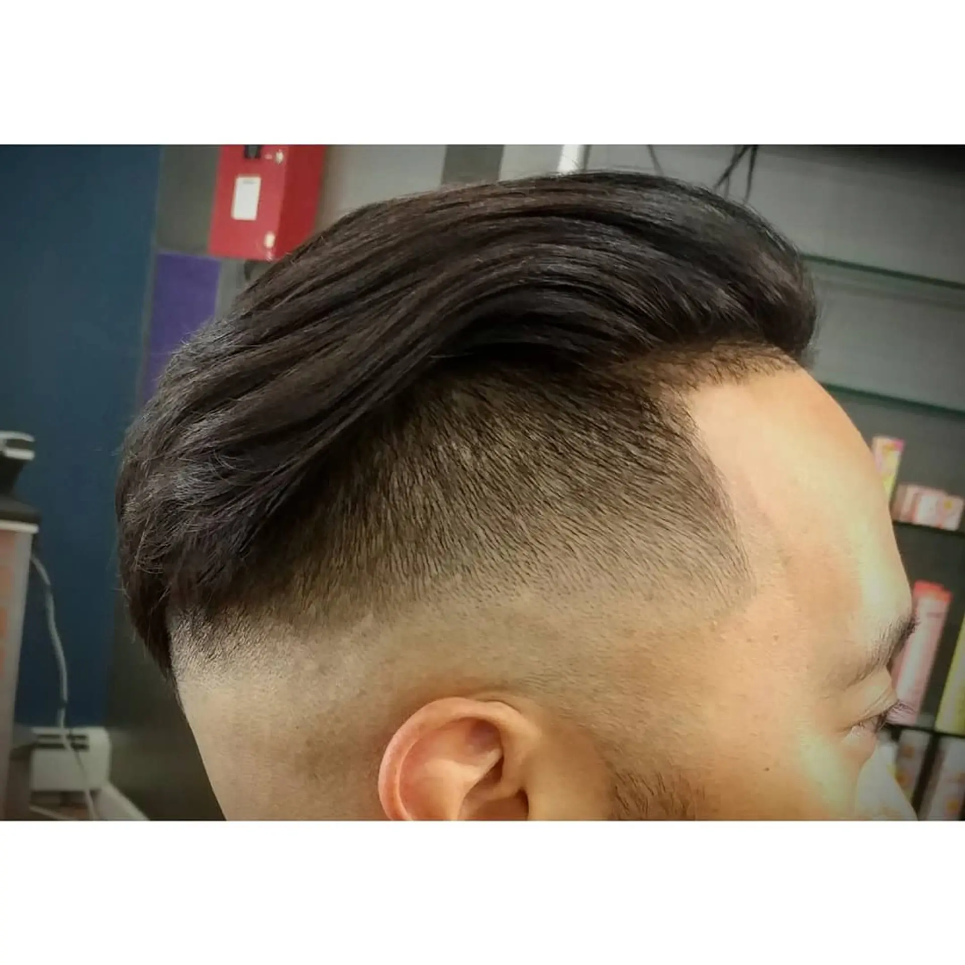 A precise skin fade along the sides blending upward into longer, slicked-back dark hair on top. 1