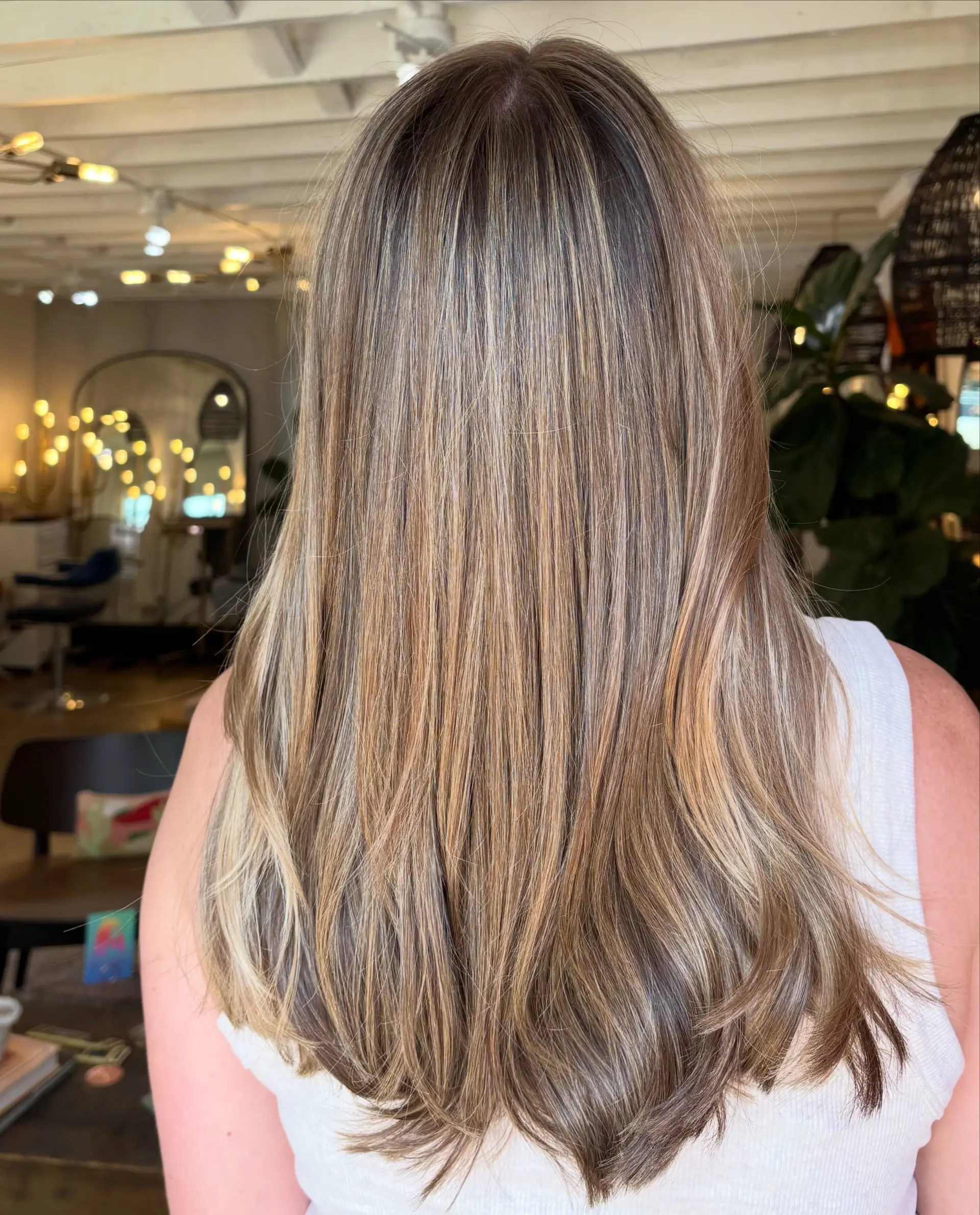 Long hair featuring fine, multi-dimensional bronde highlights styled in a sleek blowout with soft curved ends. 1