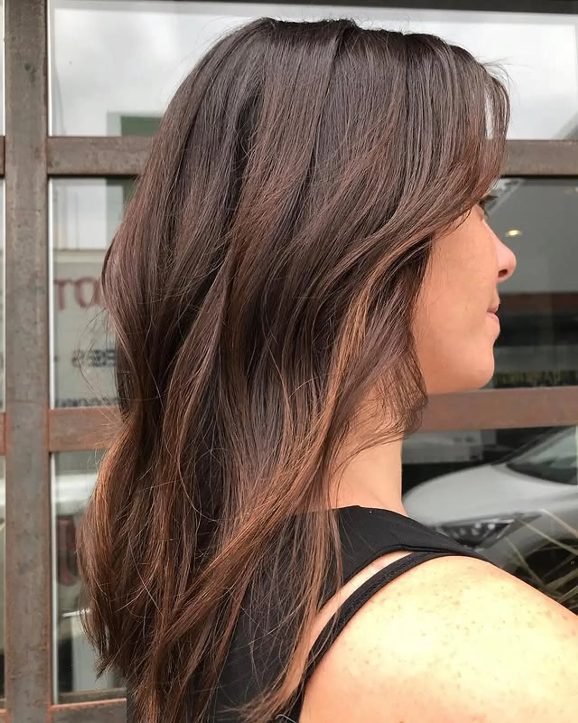 A medium-length layered hairstyle with curtain bangs and subtle waves. 1